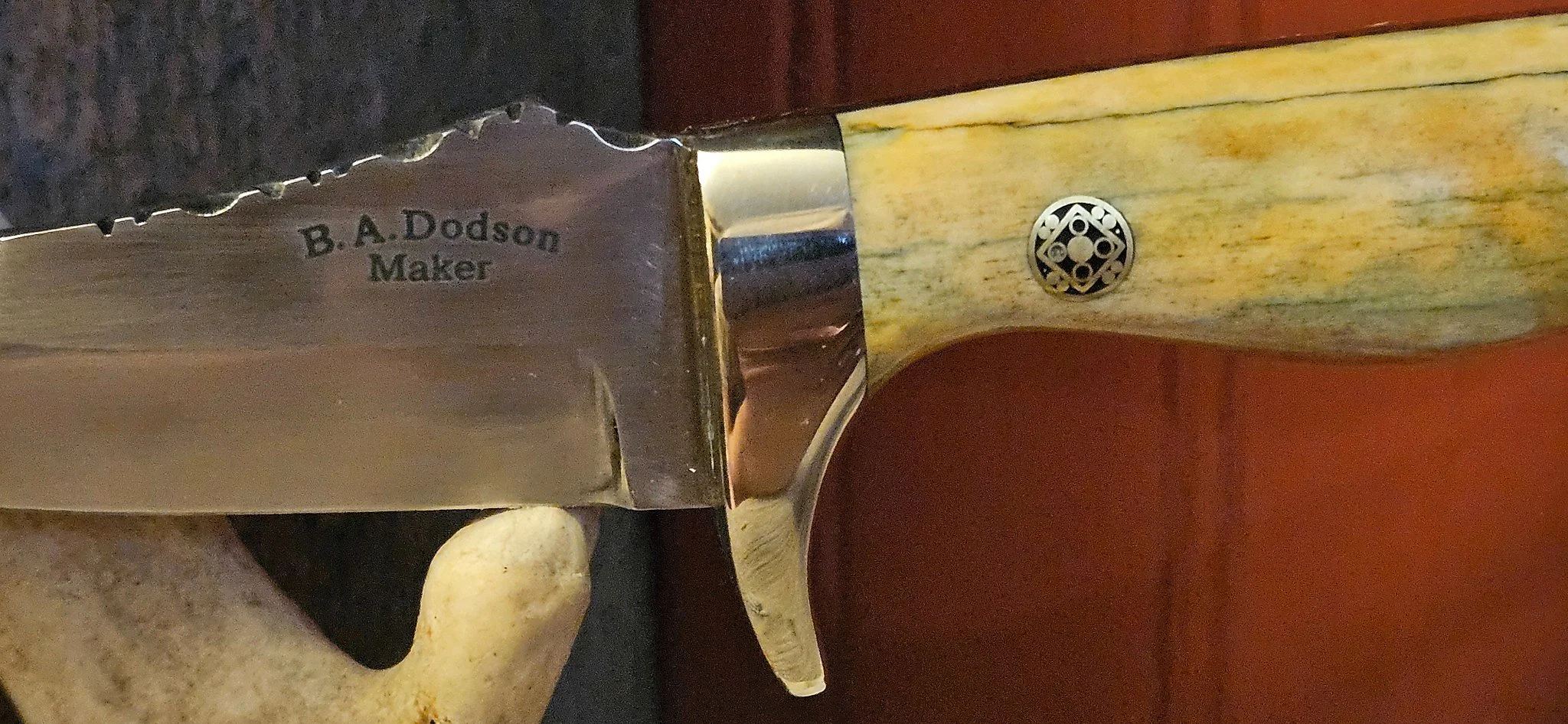 B.A. Dodson giraffe-bone fixed-blade skinner detail showing the maker’s mark, guard, decorative handle pin, and filework near the spine