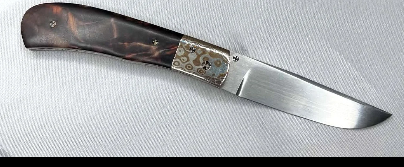 Opposite-side view of a B.A. Dodson compact cottonwood and mokume liner lock folder shown open on a white cloth background.