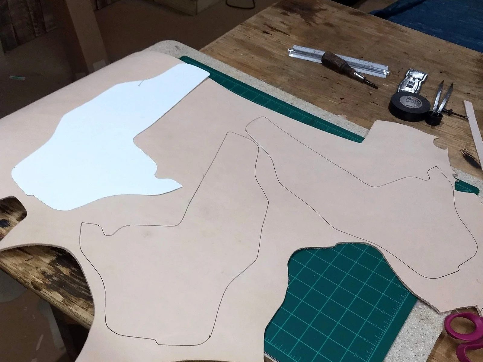 Leather sheath patterns traced on leather at Burt Dodson’s workbench for handmade B.A. Dodson knife sheaths