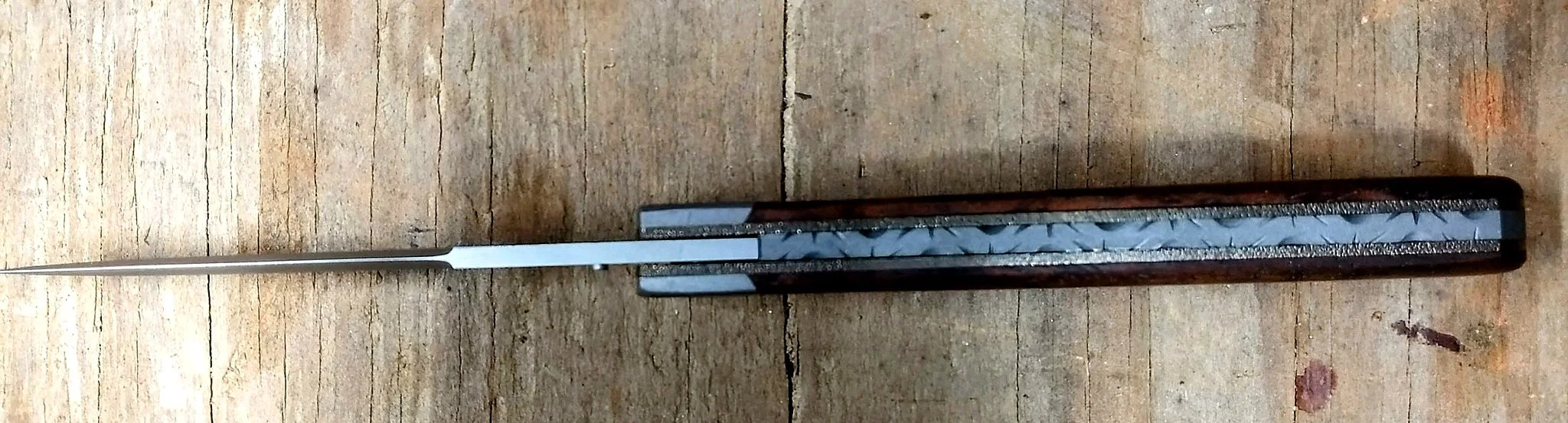 B.A. Dodson Koa wood liner lock folder viewed from the spine, showing decorative backspacer file-work and liner construction.