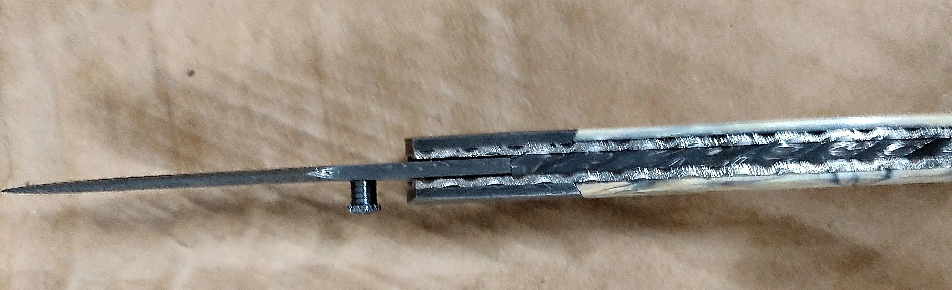 B.A. Dodson Mammoth Ivory and Damasteel liner lock folder viewed from the spine, showing decorative backspacer file-work and mammoth ivory handle scales.