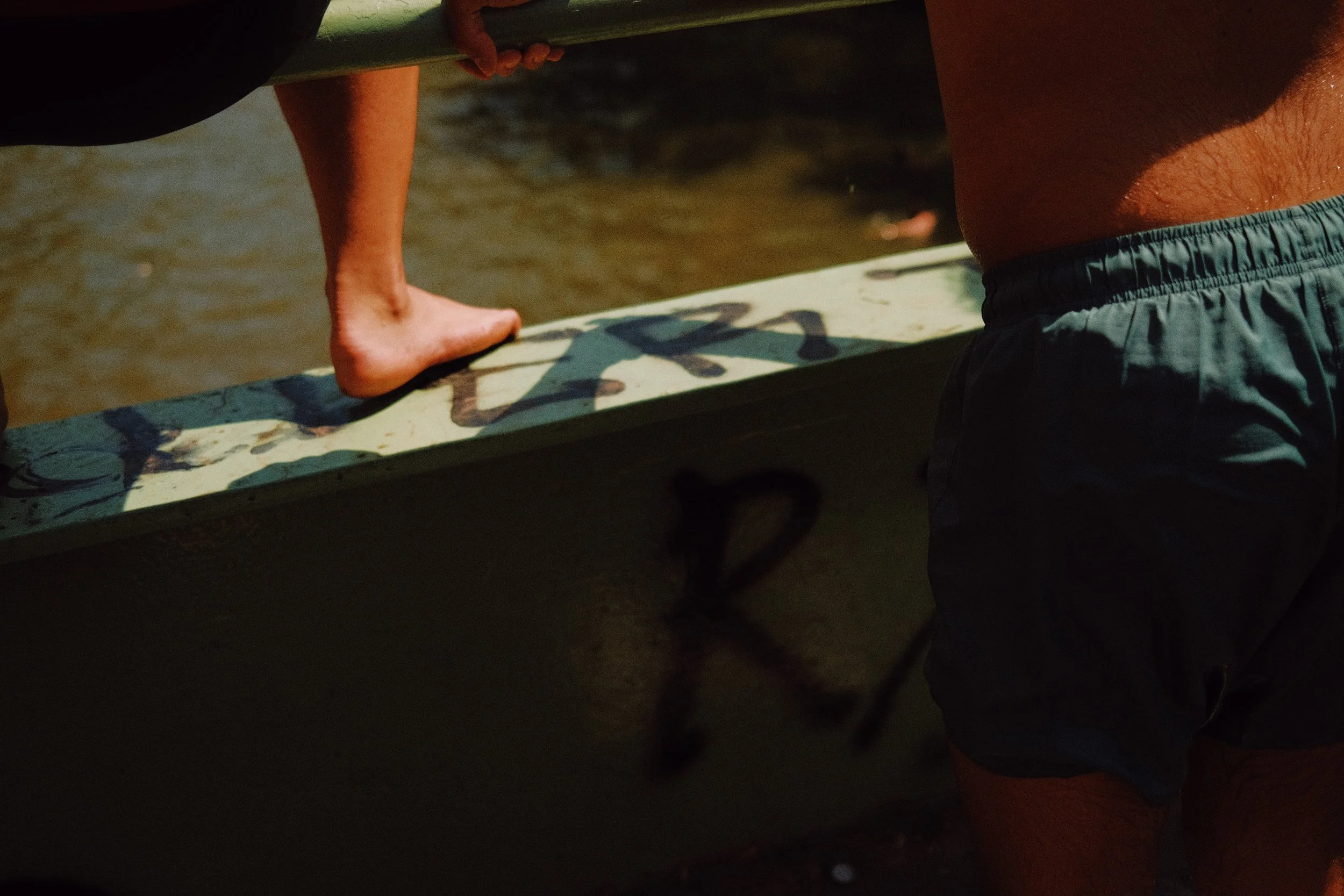 Une personne portant un maillot de bain court, portant un short et portant une planche de surf, est près de l'eau de mer.