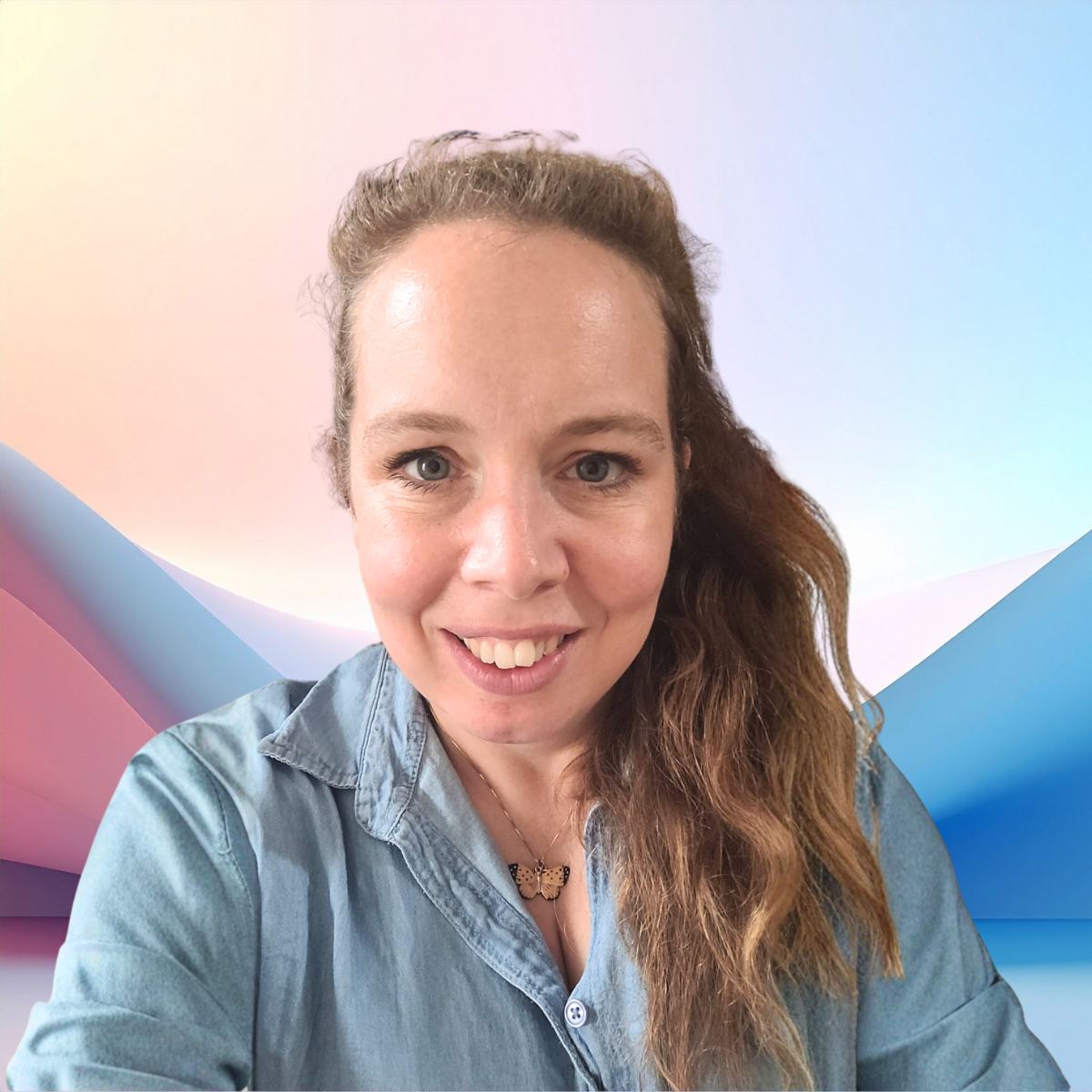 A photograph of Katie Gowers; a woman with long brown hair smiling, wearing a denim shirt and a butterfly necklace, in front of a colourful abstract background.
