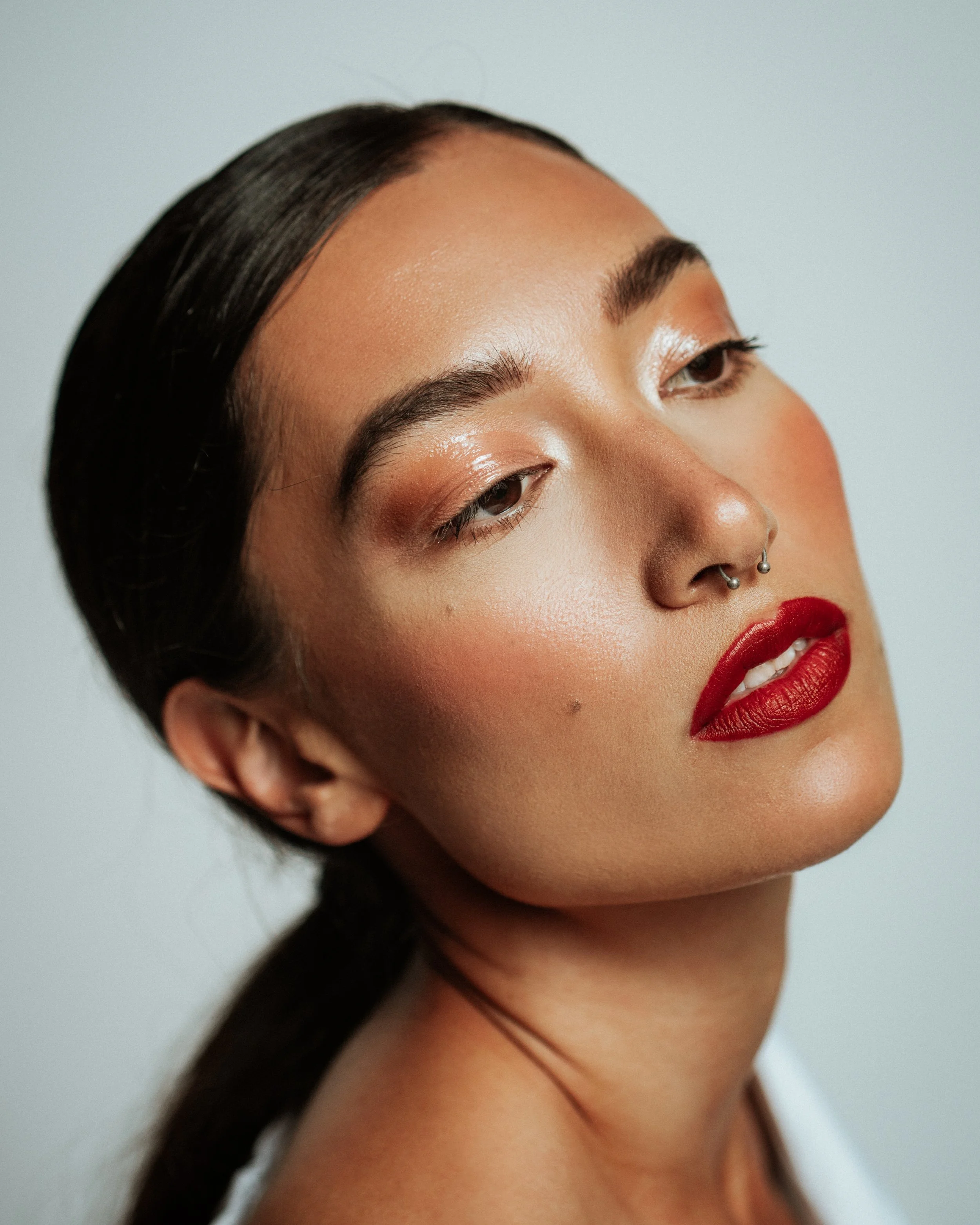 Bold red lip and clean complexion showcasing classic beauty. Detail oriented makeup applied with precision by Kinga, ideal for lipstick and cosmetic campaigns.
