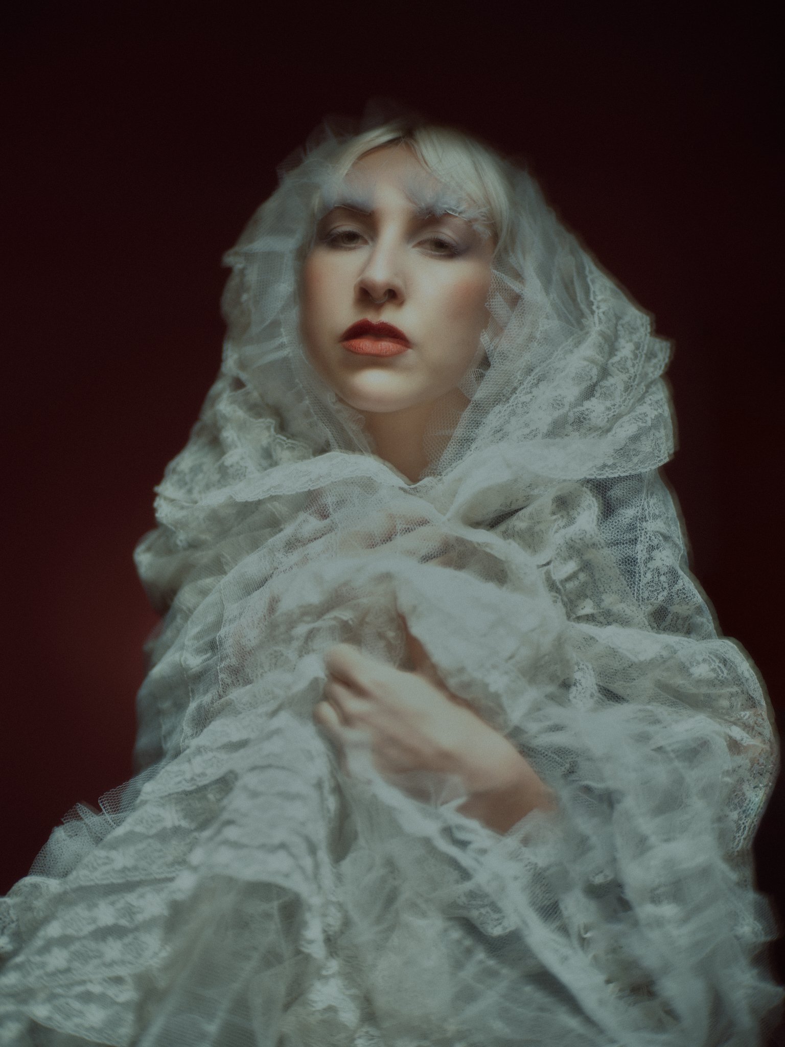 Dramatic editorial makeup by Kinga featuring sculpted skin, deep red tones, and bold fashion styling. A refined, expressive editorial look.