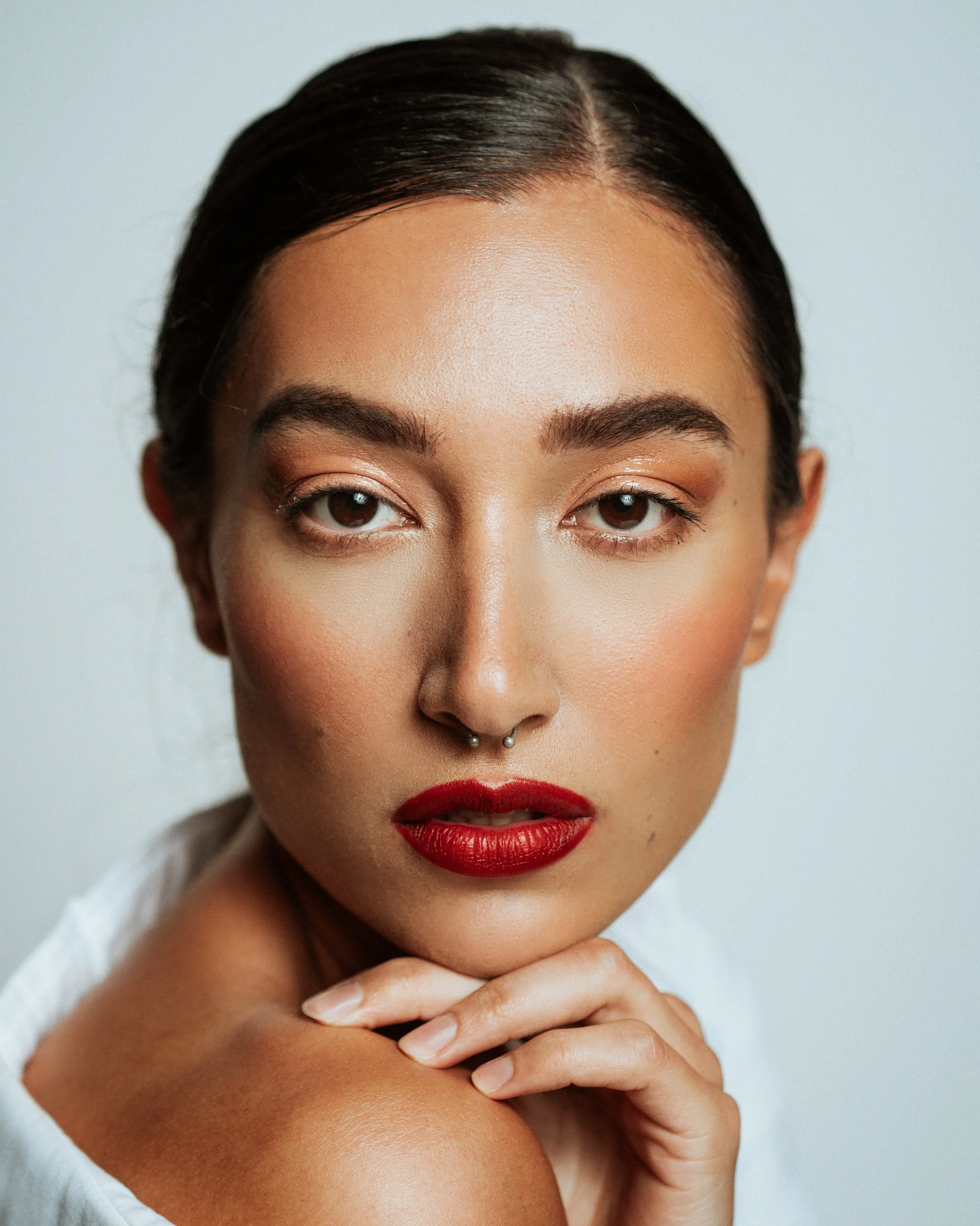 Bold red lip and clean complexion showcasing classic beauty. Detail oriented makeup applied with precision by Kinga, ideal for lipstick and cosmetic campaigns.
