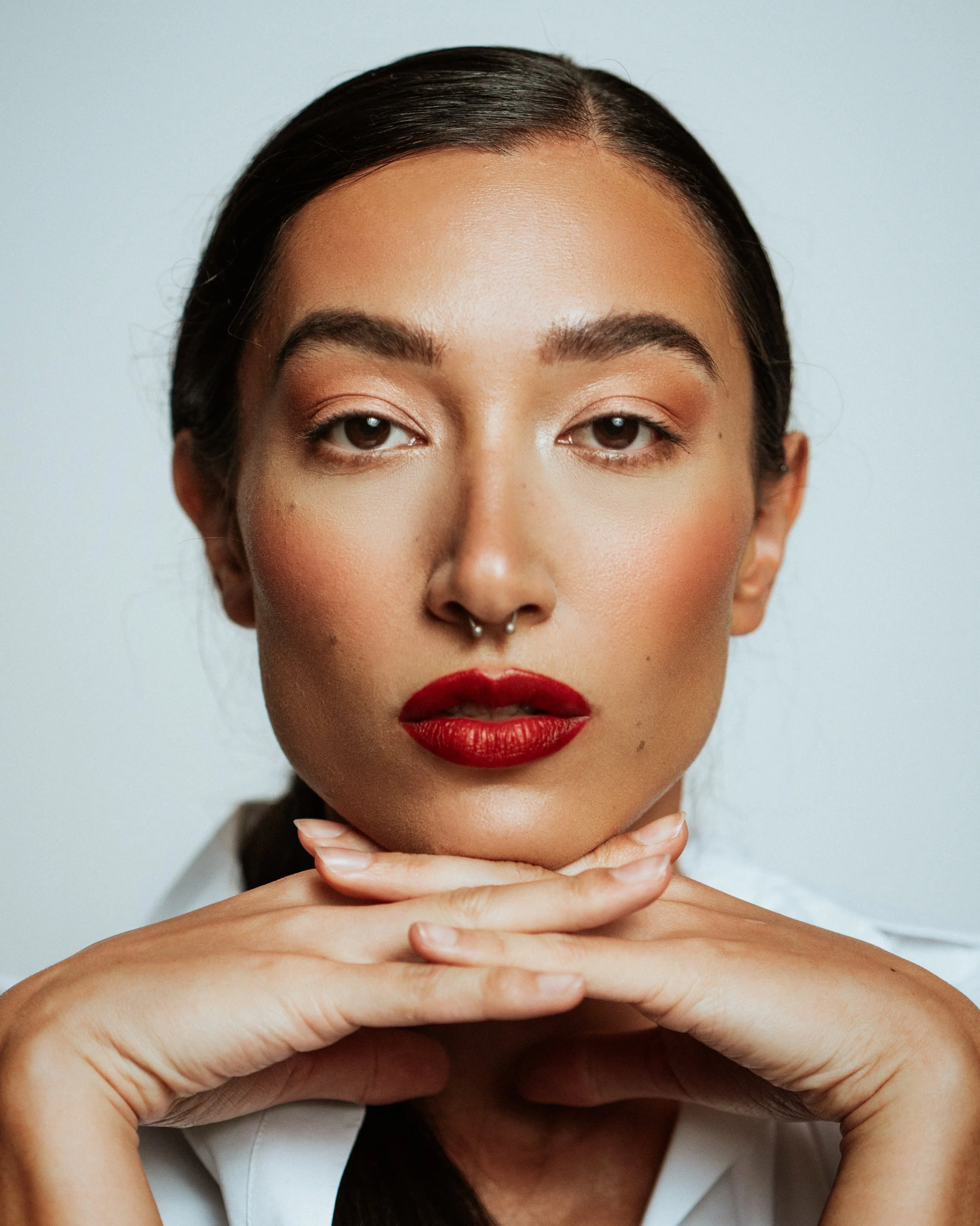Bold red lip and clean complexion showcasing classic beauty. Detail oriented makeup applied with precision by Kinga, ideal for lipstick and cosmetic campaigns.