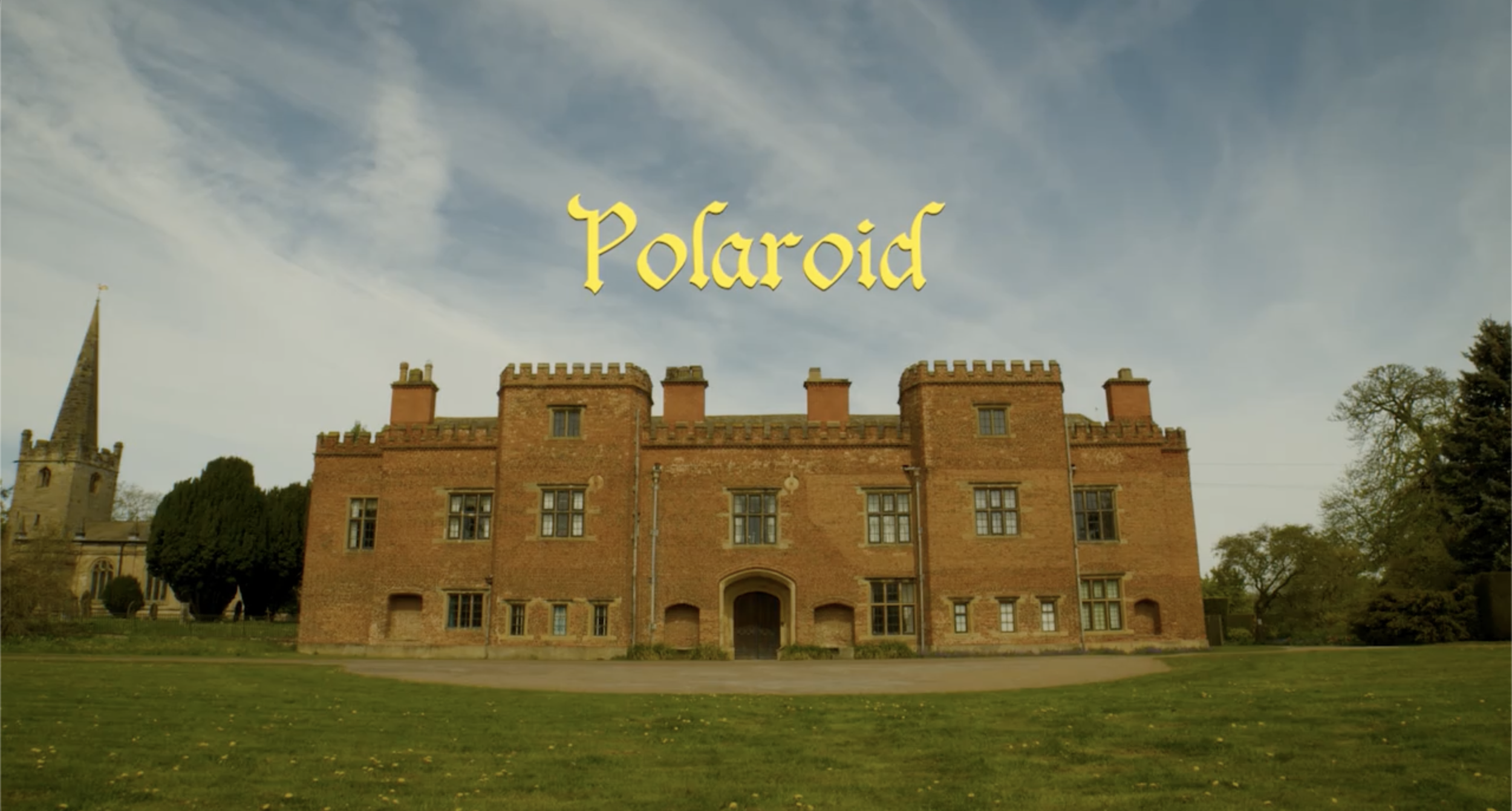 Image of a red-brick castle with a grassy foreground and a cloudy sky, with the word 'Polaroid' in yellow text in the center.