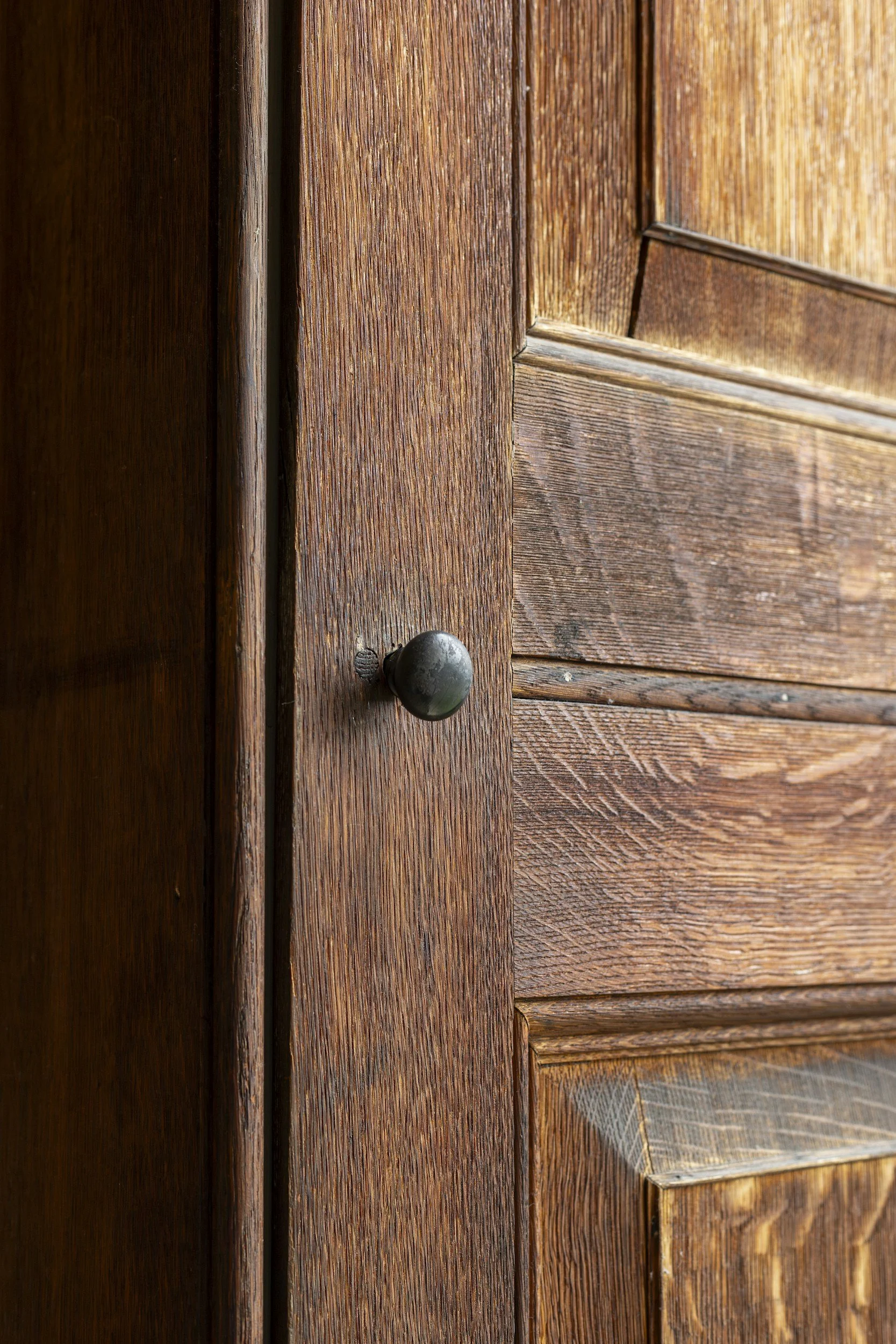 Close-up of wooden door with textured wood grain and a black door knob.