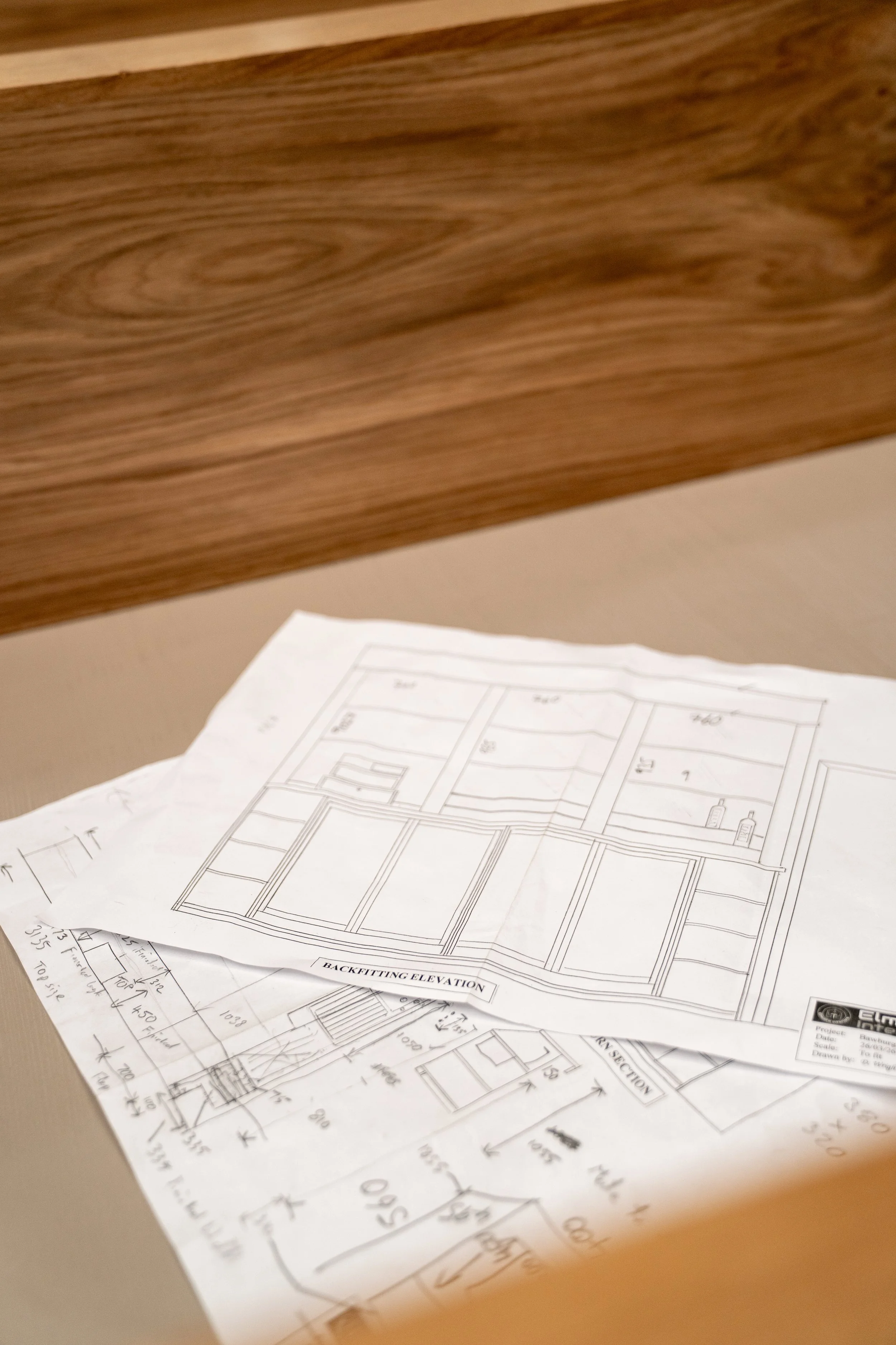 Blueprints and architectural drawings on a wooden table.