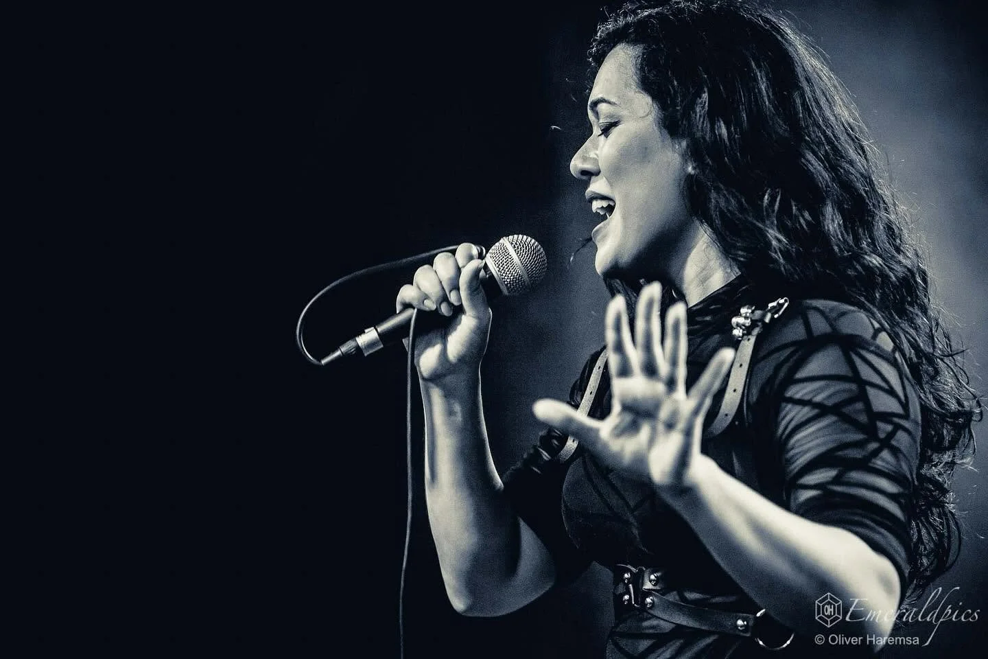 A woman singing into a microphone on stage, black and white photo.