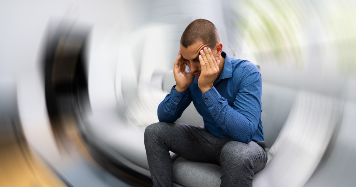 A man sitting alone inside a tunnel with a distressed expression, holding his head with both hands.