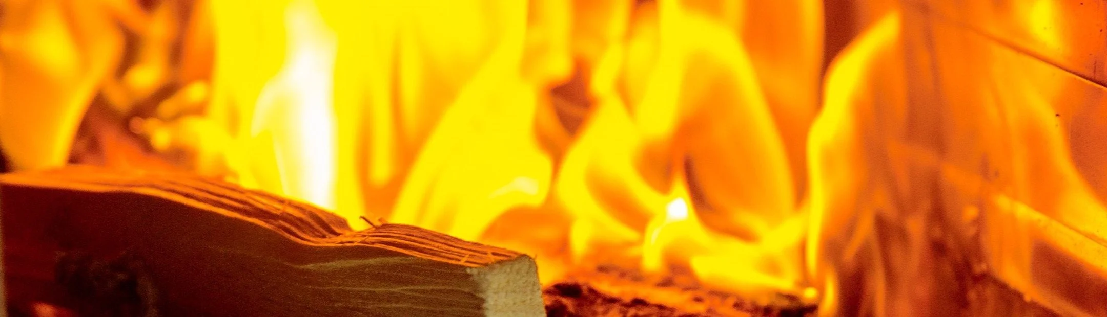 A close-up of a campfire with bright orange and yellow flames burning around logs.
