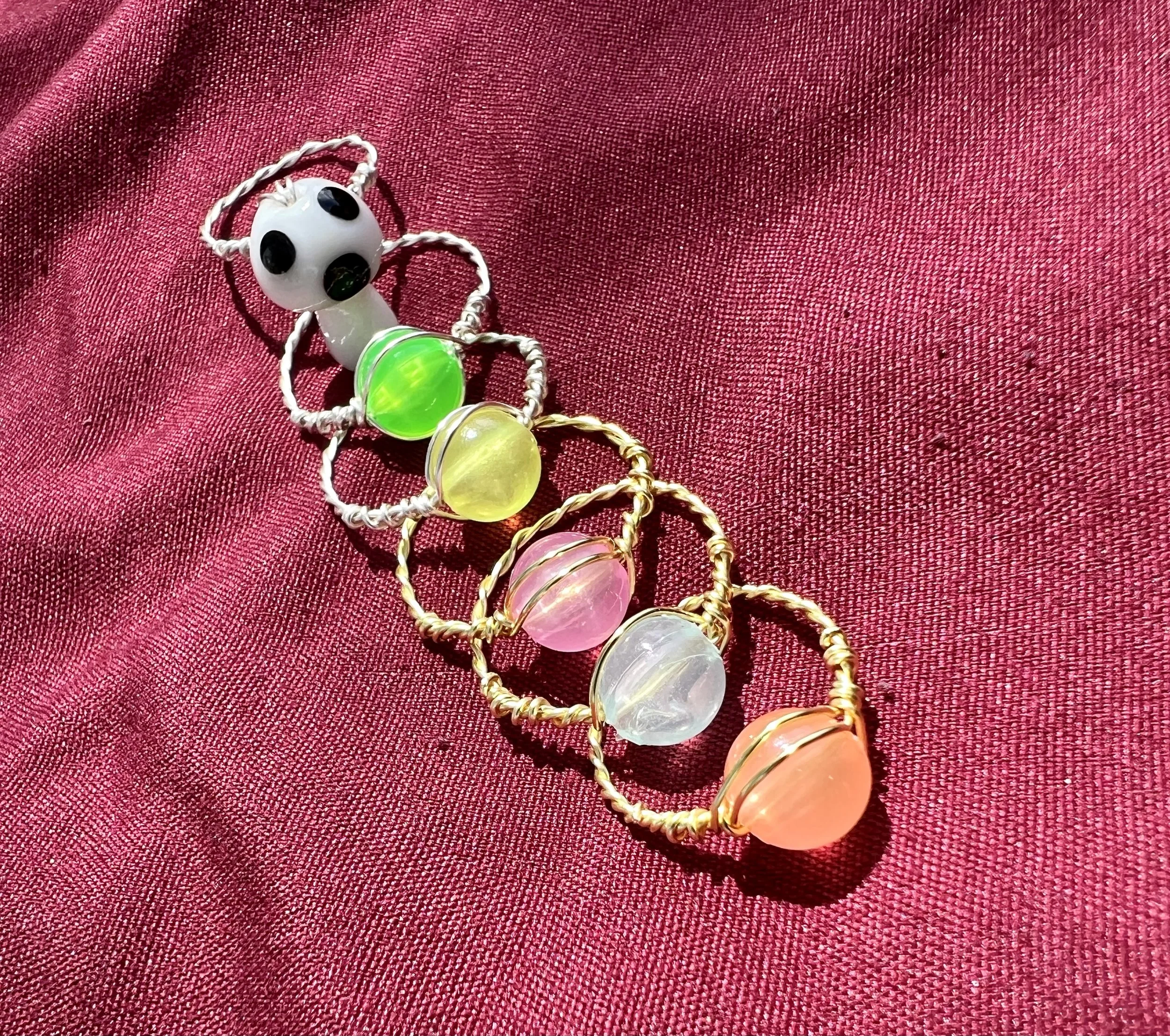 A collection of colorful beaded bracelets with gemstone beads on red textured fabric.