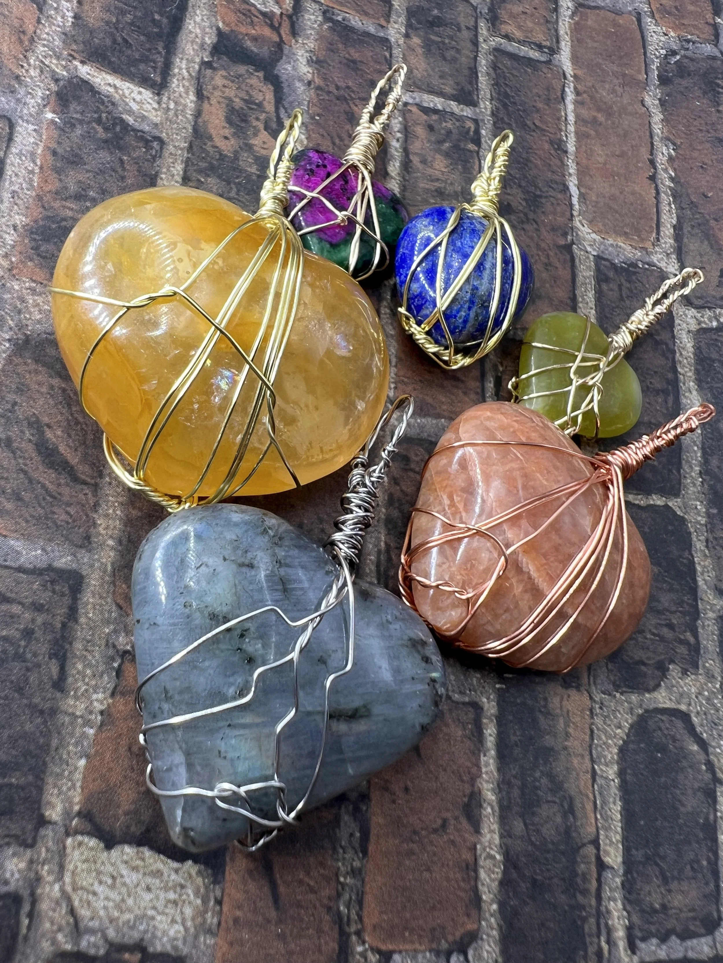 Colorful stones wrapped with wire and arranged on a brick surface.