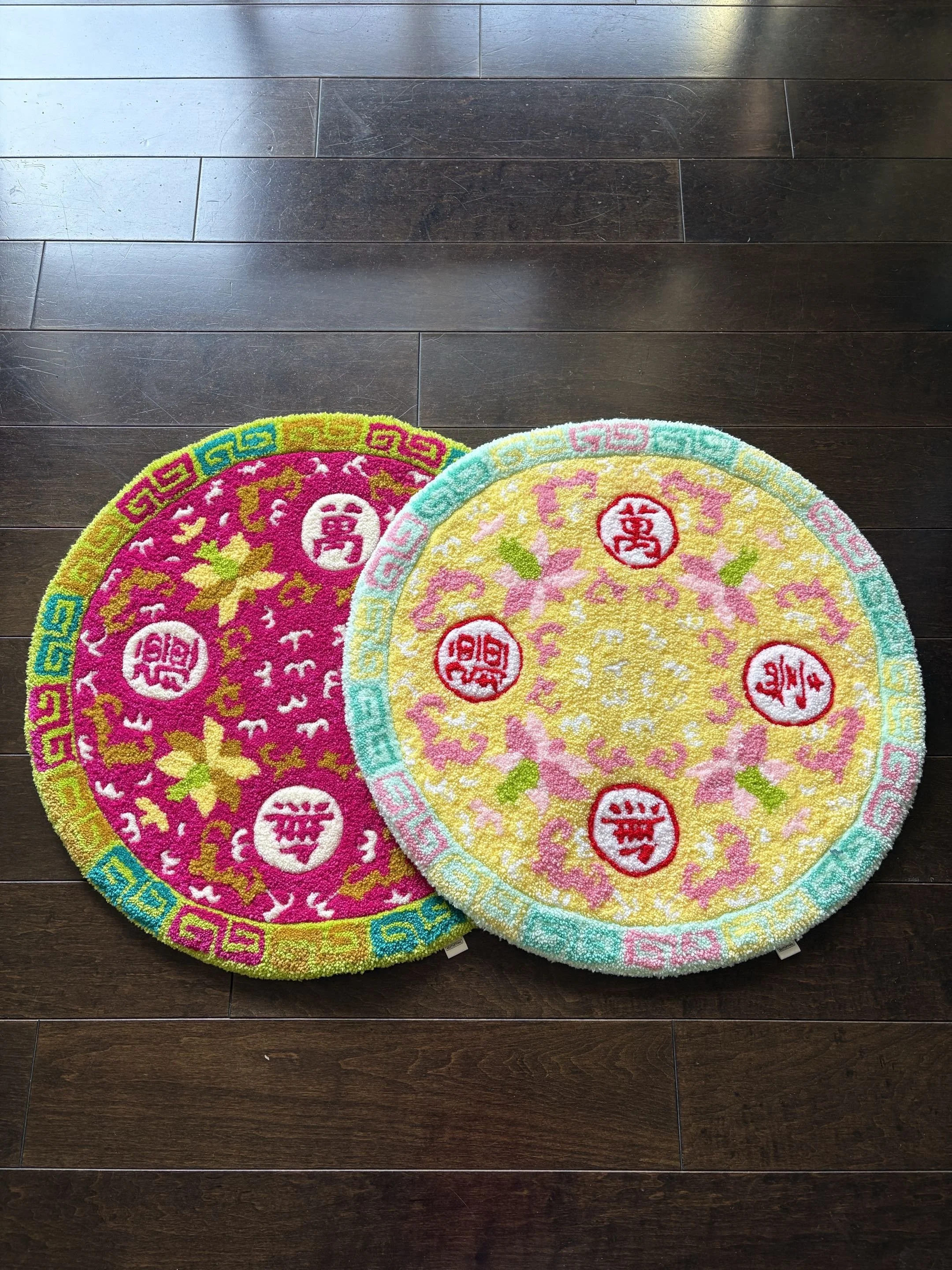 Two colorful round rugs with Boundless Longevity patterns on a dark wooden floor.