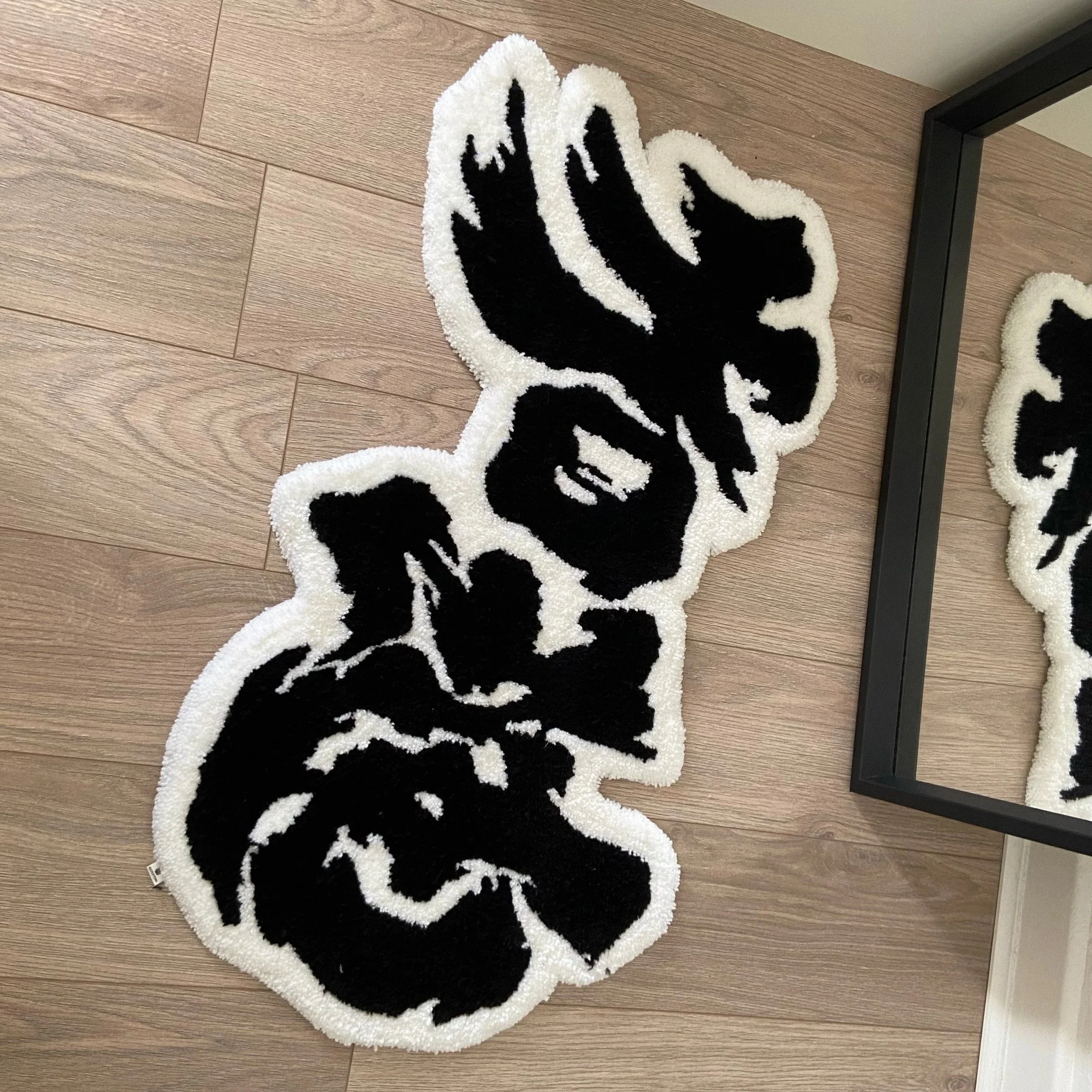 Black and white Chinese calligraphy rug on a wooden floor next to a mirror