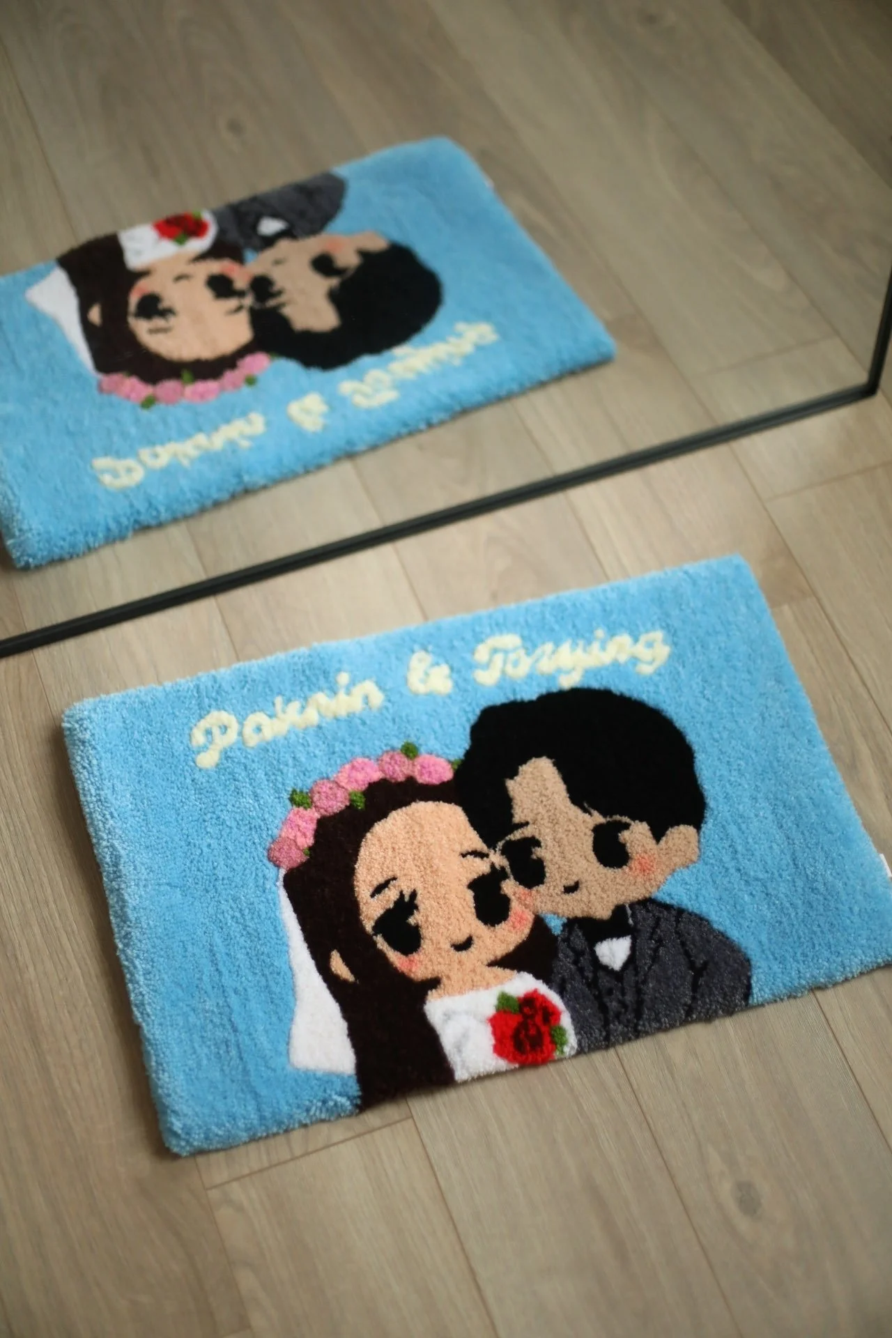 Blue rug with cartoon of a bride and groom kissing, with the words 'Pakin & Toming' written above them.