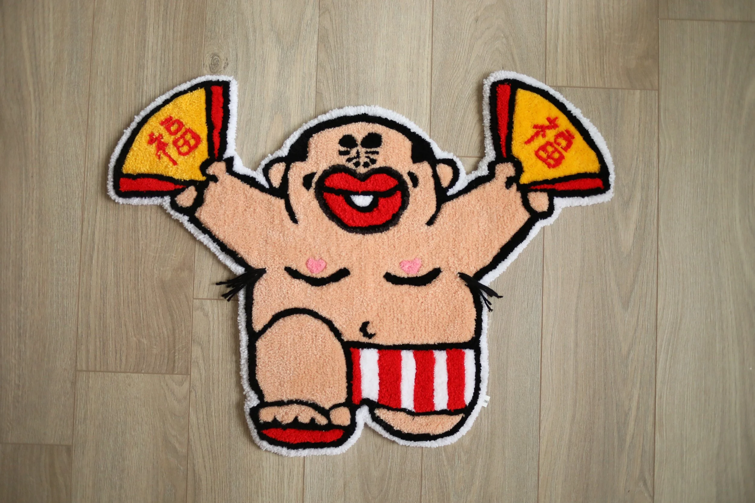 A funny floor rug featuring a cartoon-style character of a person with a sunhat and red lips, holding a yellow fan with red and black accents, standing inside a red frame.