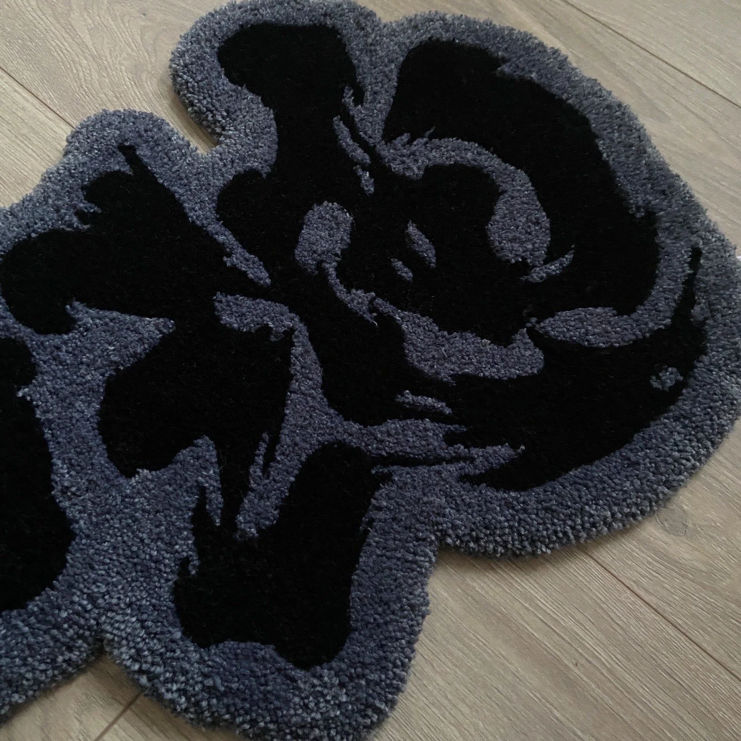 Black and gray Chinese calligraphy rug placed on a light wooden floor.