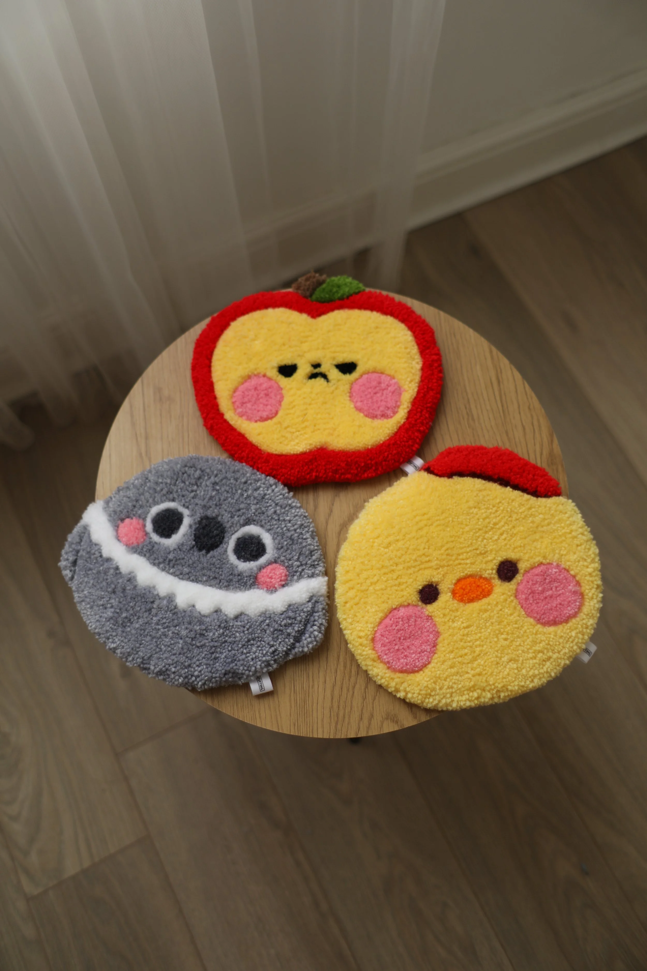 Four round plush towels with animal faces and a character in a pumpkin dress, placed on a wooden stool.