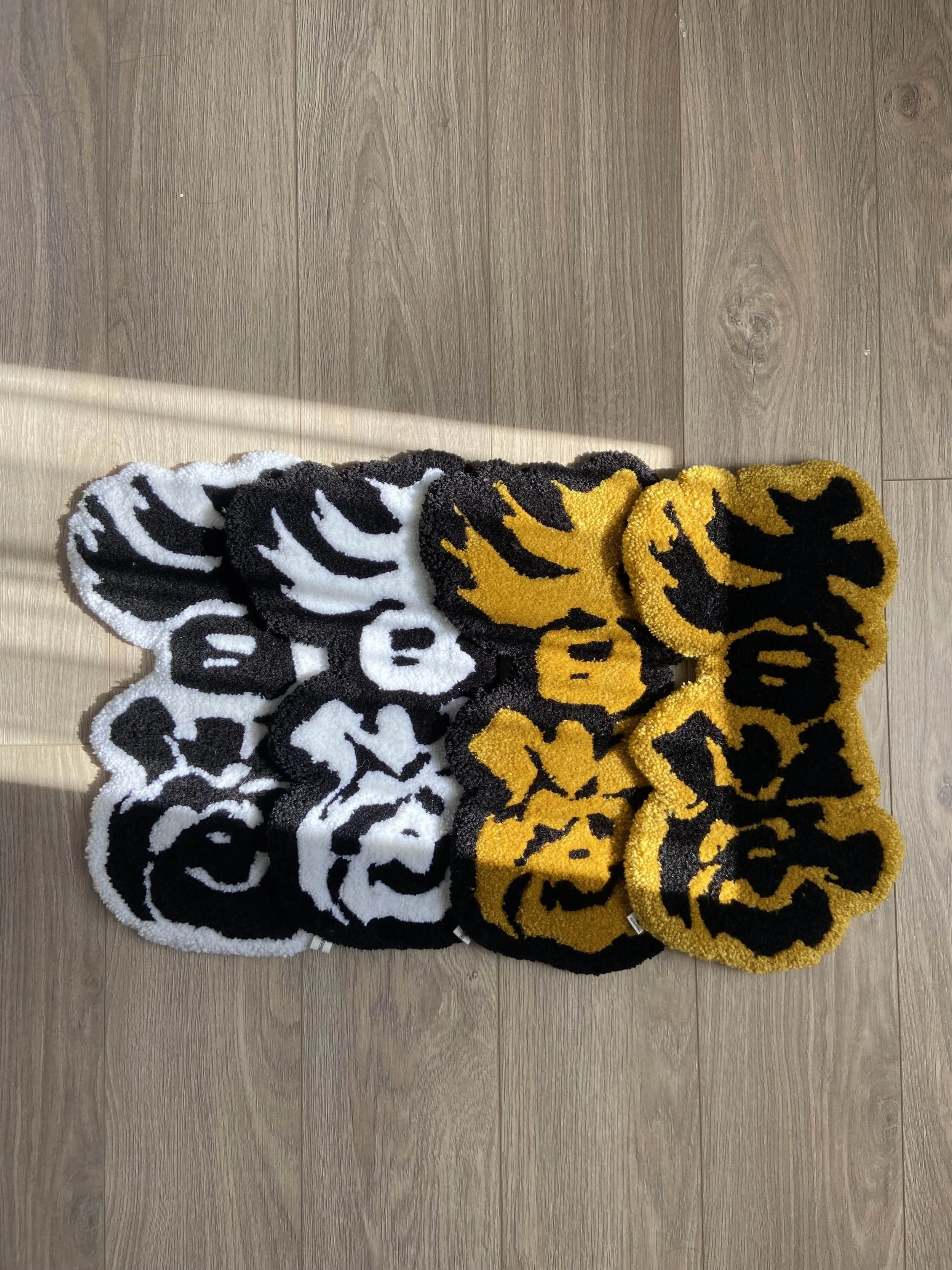 Floor rugs with Chinese calligraphy in black, white, and gold colors arranged on a white background. placed on a wooden floor.