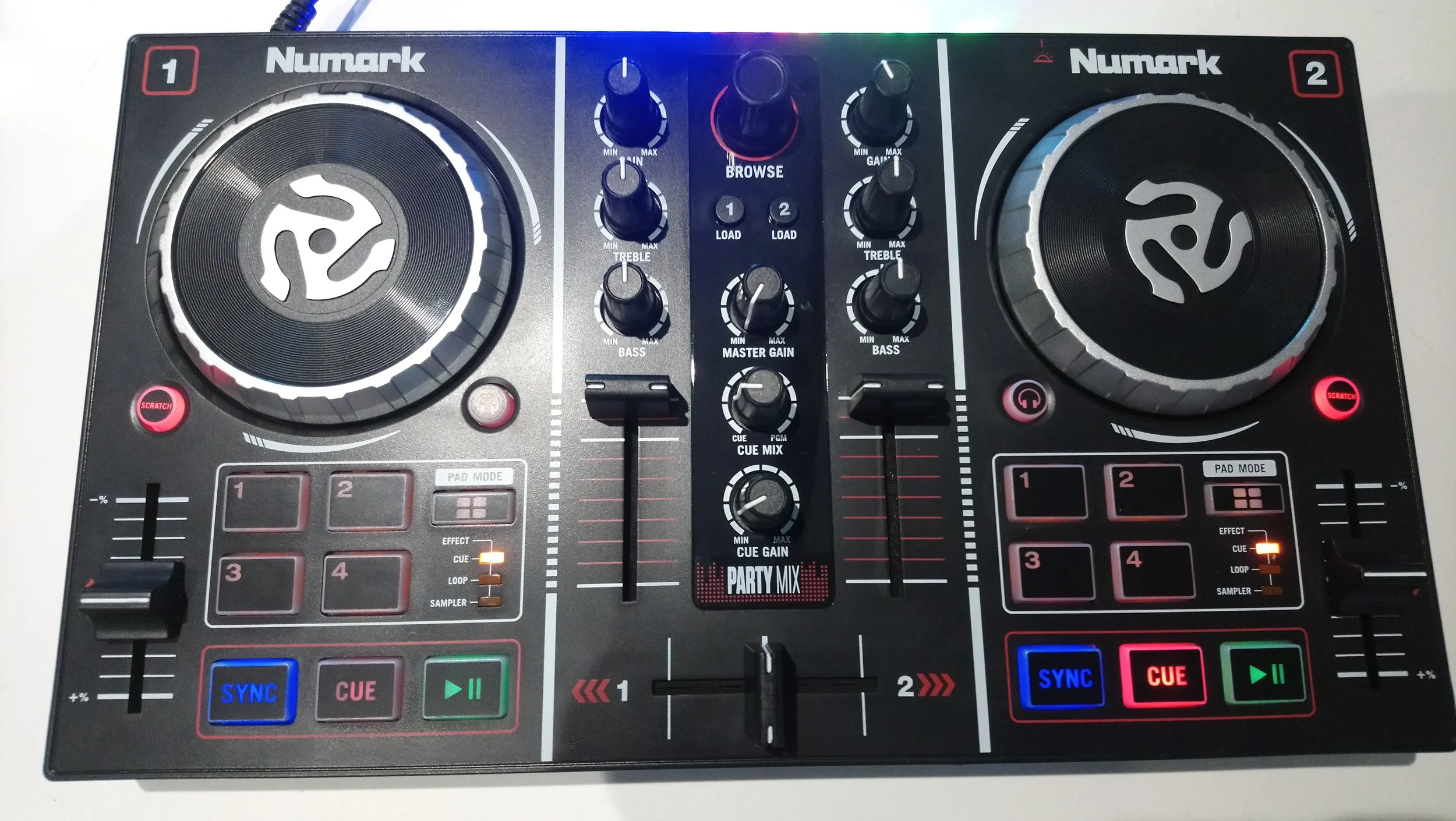 A DJ mixing console with two large jog wheels, various knobs, sliders, and buttons, including color-coded cue buttons, effects, and synchronization controls.