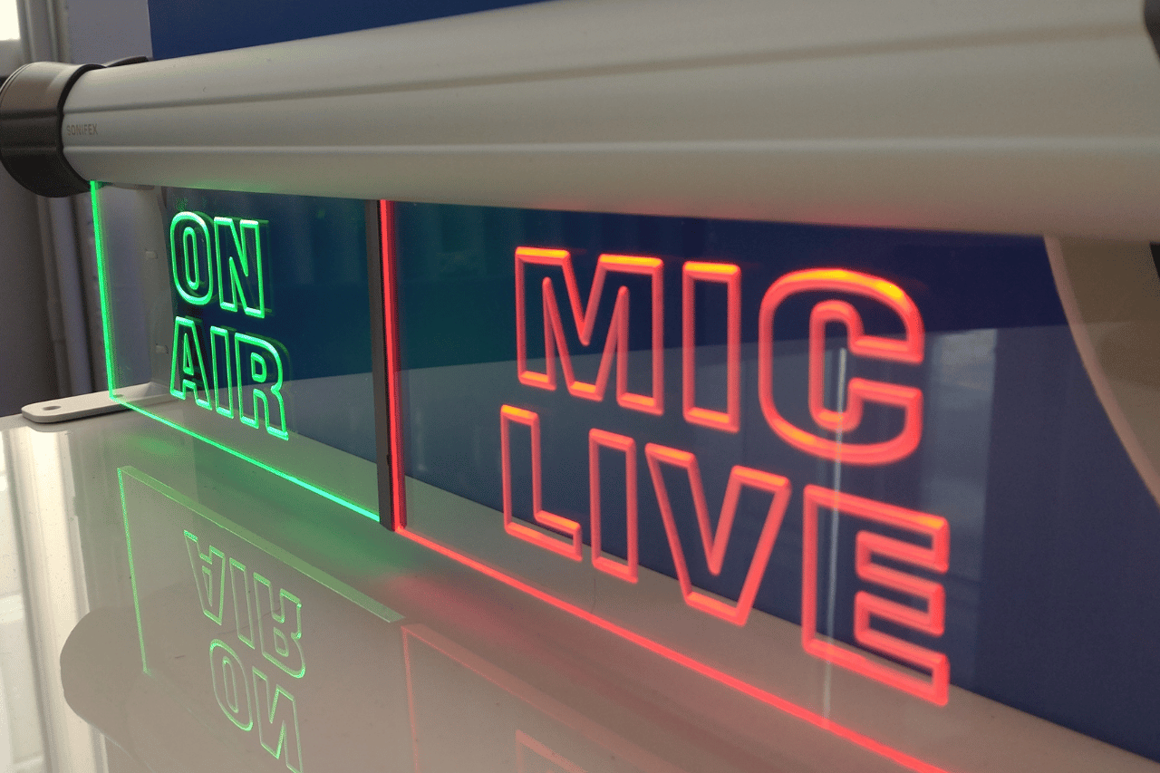 Neon sign with green letters that reads 'ON AIR' and red letters that reads 'MIC LOVE'