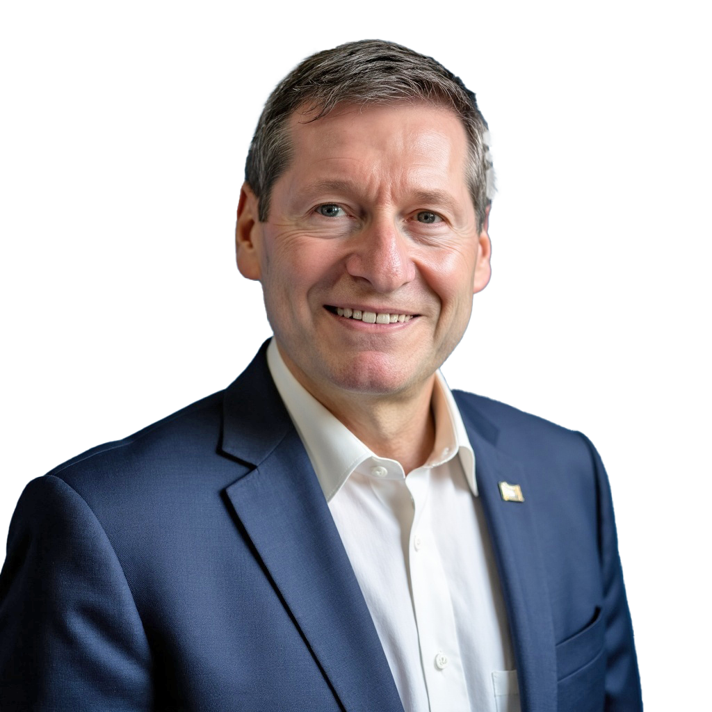 A smiling middle-aged man in a navy blue suit with a white shirt, standing against a background with a stylized American flag design.