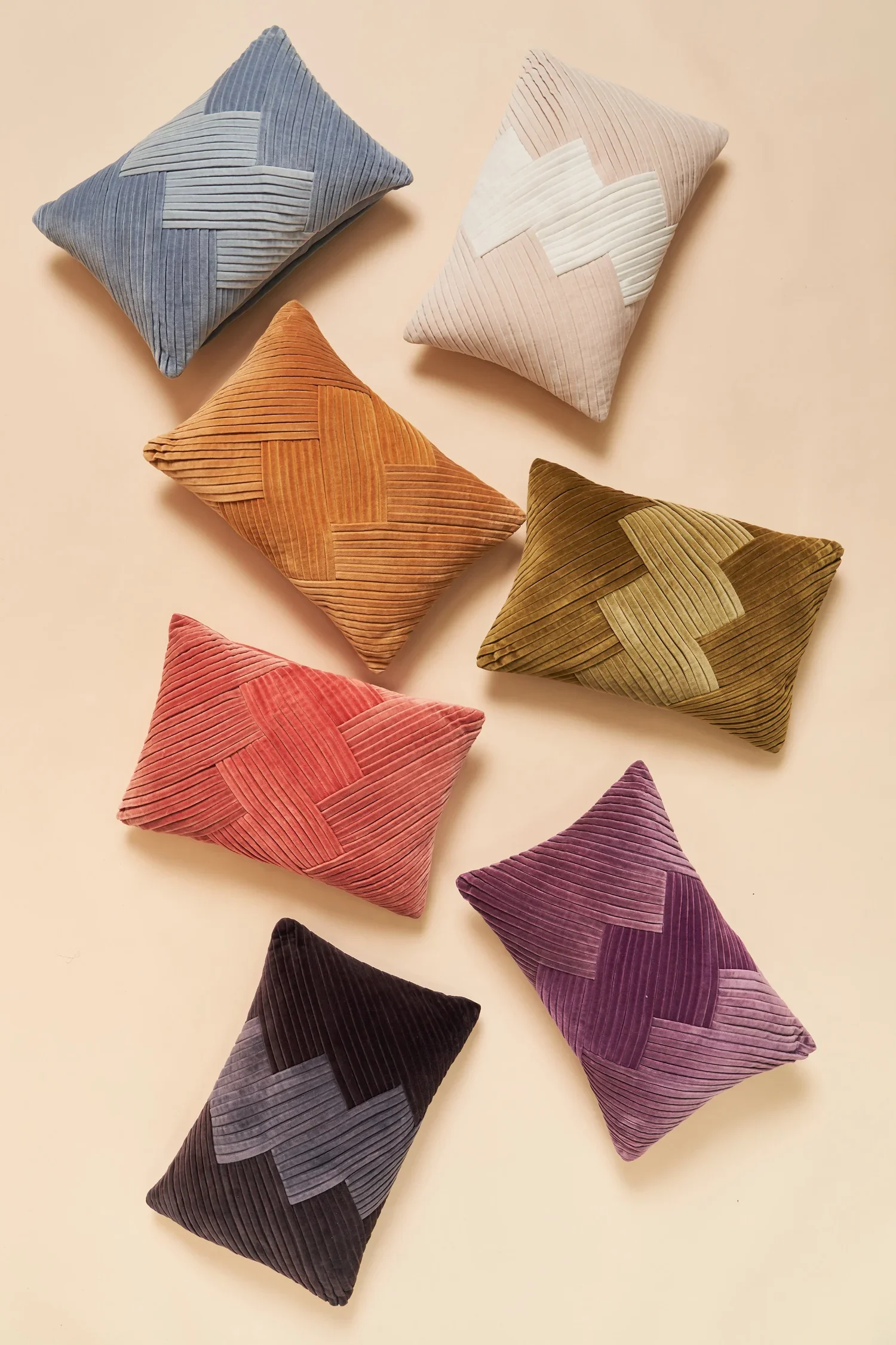 Six decorative pillows with corduroy fabric in various colors, arranged on a beige background.