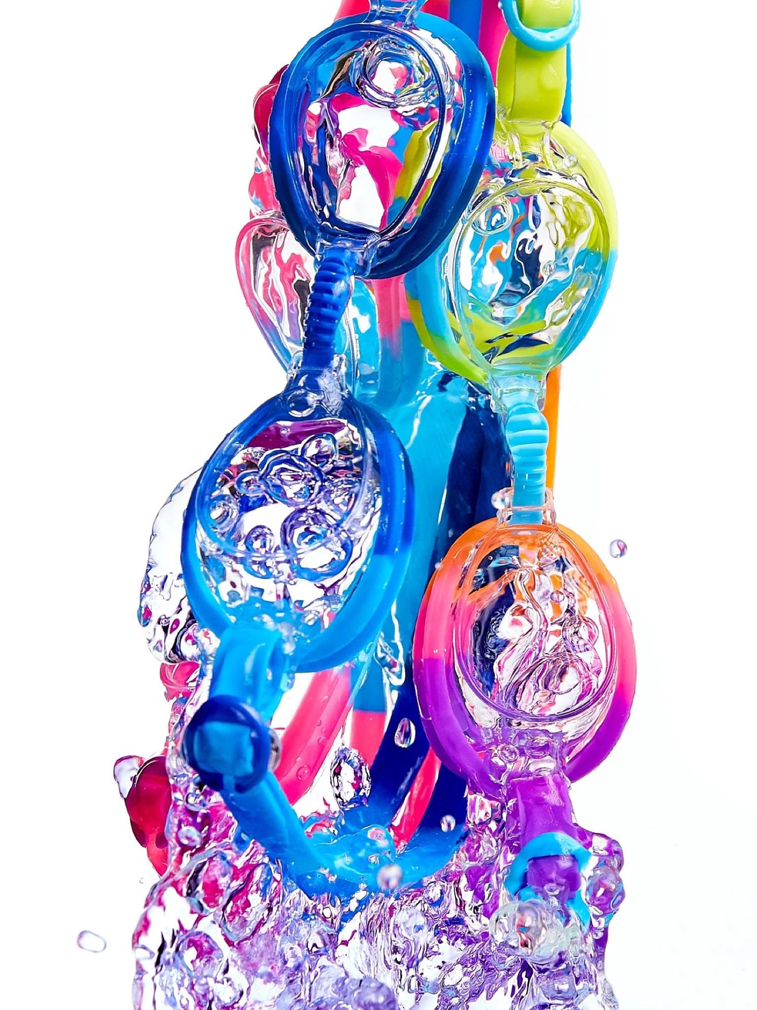 Colorful water splash with pink, blue, green, purple swimming goggles and orange hues against a white background.