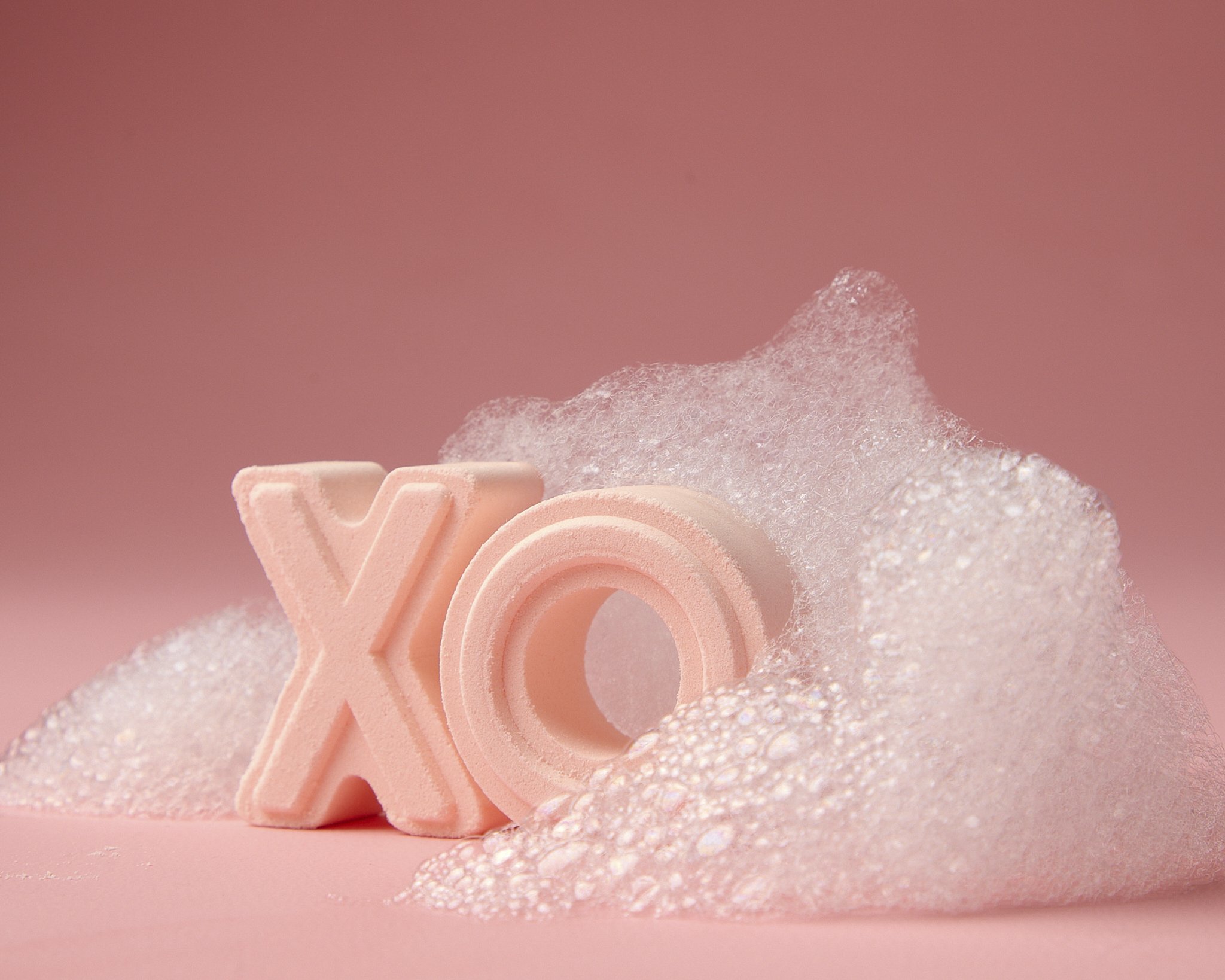 Close-up of pink foam letters spelling out 'LOVE', with textured foam and glittery pink surface in the background.
