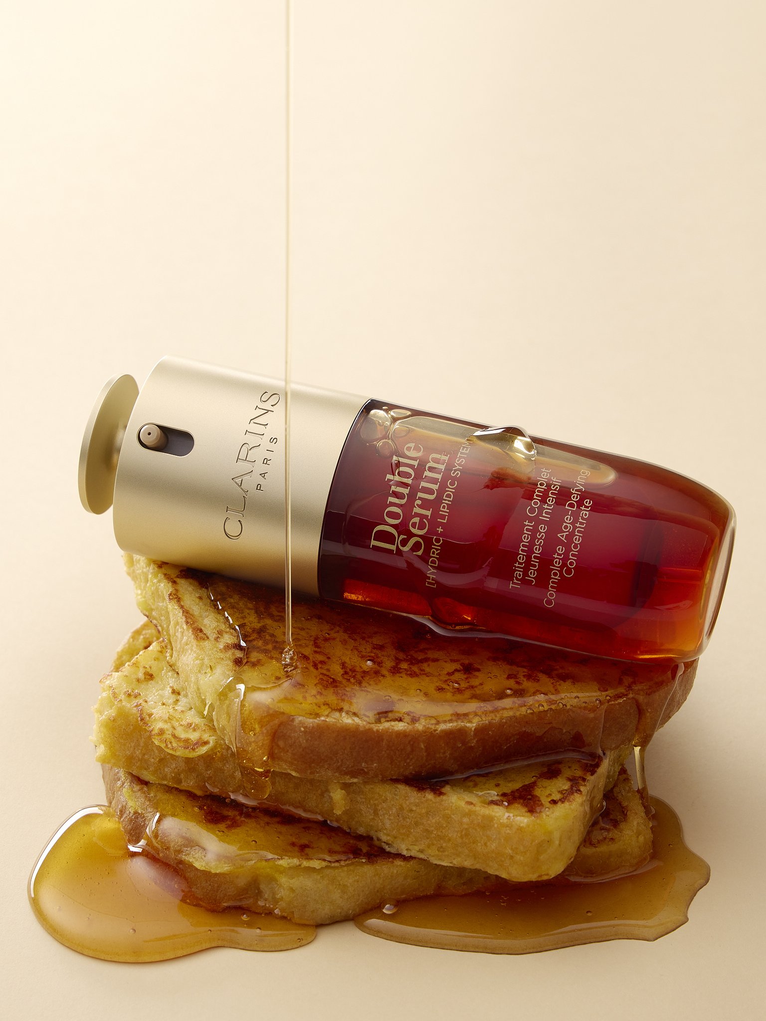 three stacked slices of French toast, covered with a maple syrup, and a bottle of Clarins on top.