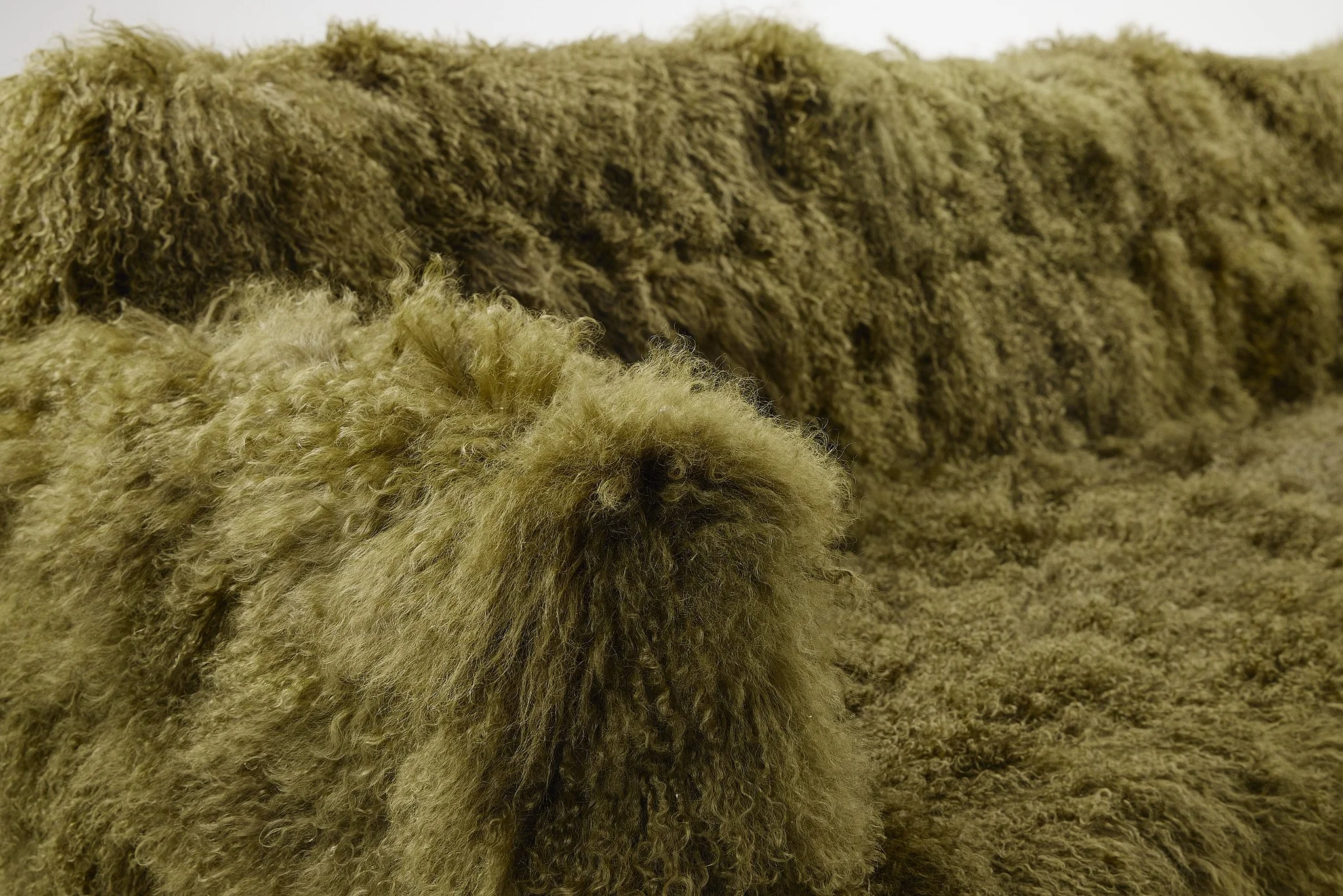 Close-up of thick, curly, and textured brown and beige Mongolian yak fur upholstered couch.