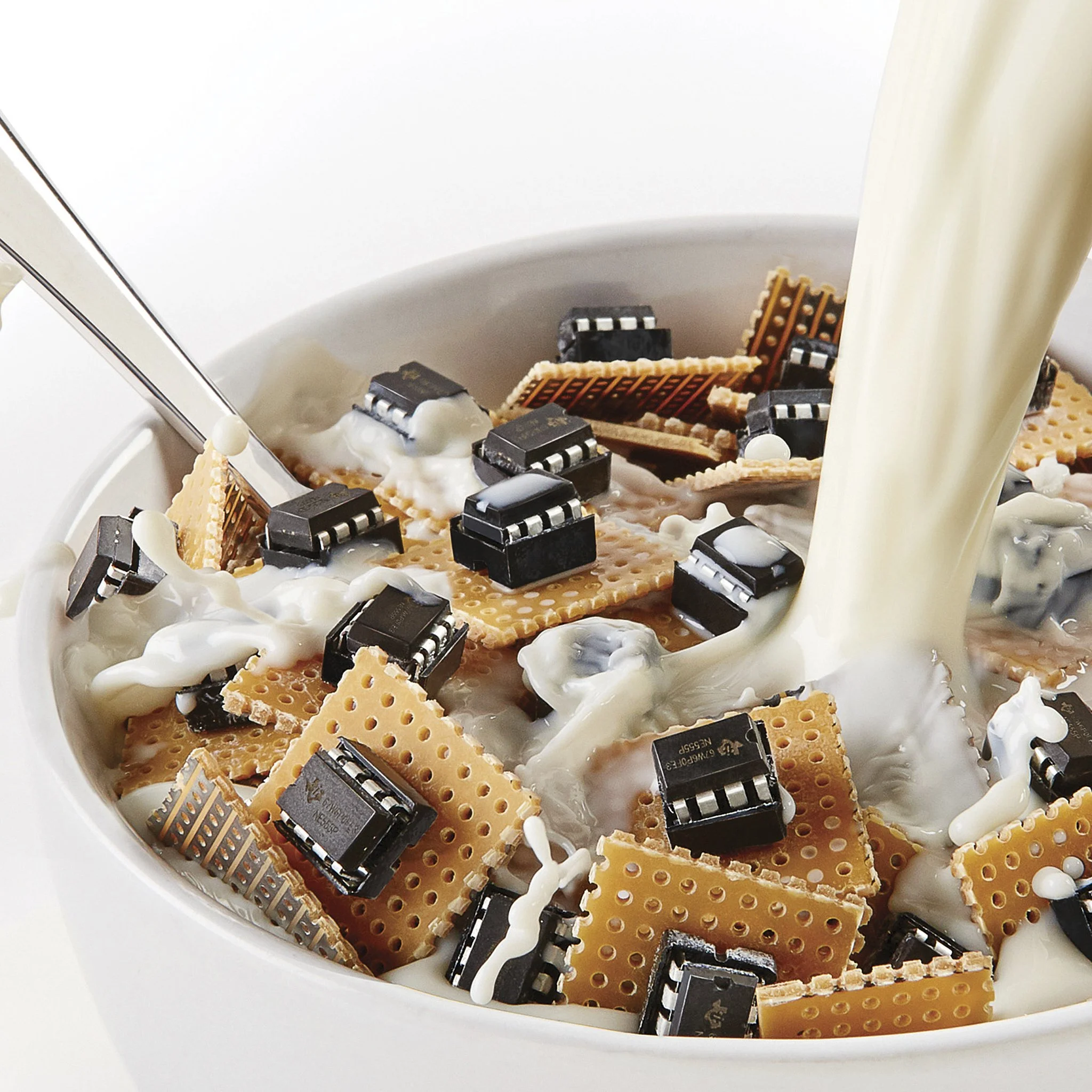 Close-up of computer chips and wafers in a white bowl with milk pouring in.
