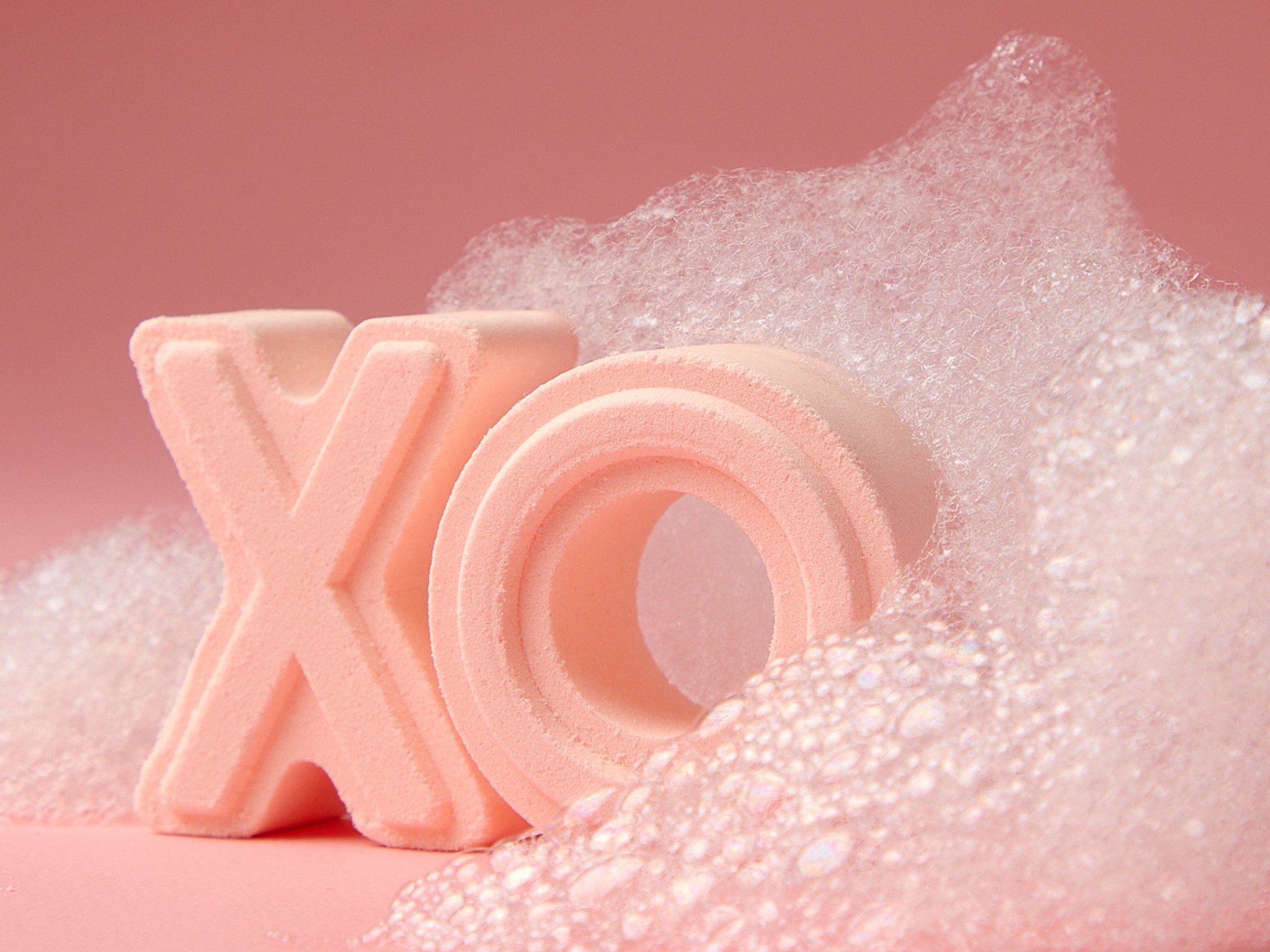Close-up of pink foam rollers with a bubble material on a pink background.