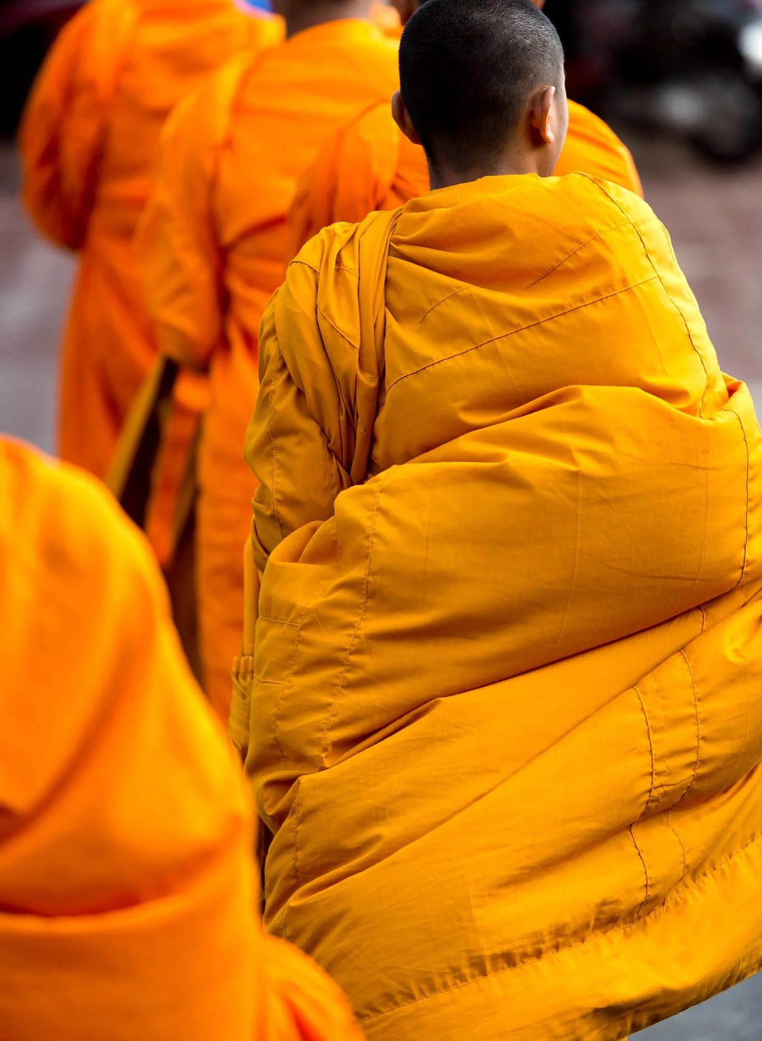 Back view of a novice monks in Phnom Phen Cambodia,  standing among other similarly dressed individuals, with a blurred background.