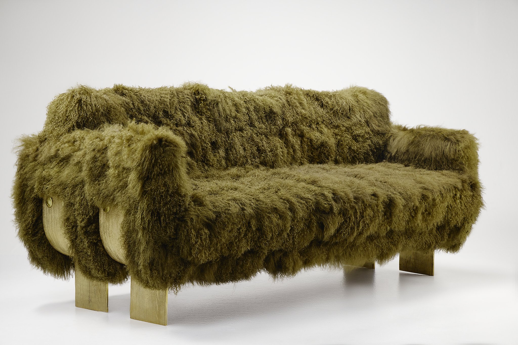 A piece of furniture made with bronze legs and covered in thick, curly, brown Mongolian yak fur.