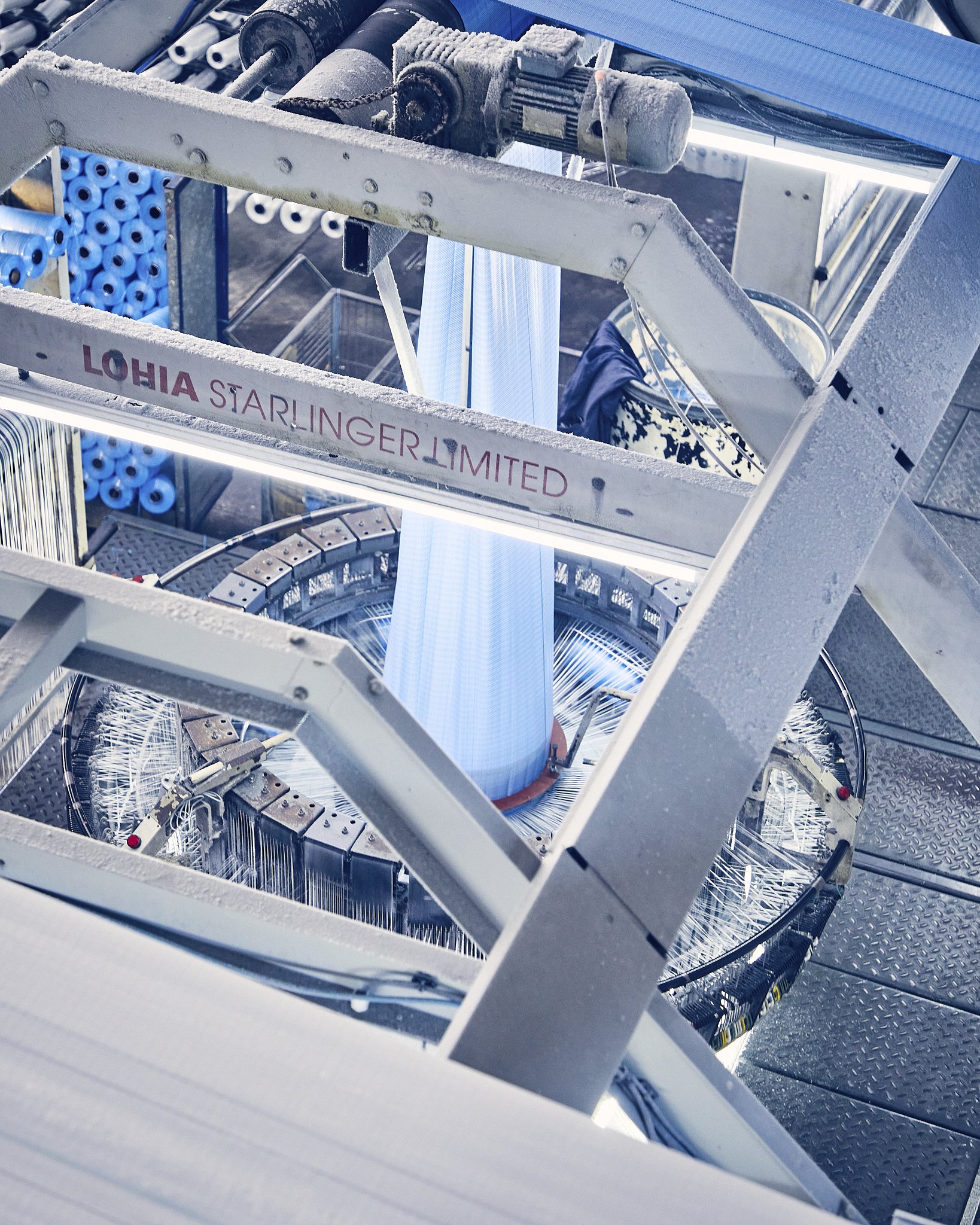 A close-up of industrial machinery with metallic parts, hoses, and a conveyor system covered in frost, with a pending or ongoing process of freezing or cooling.