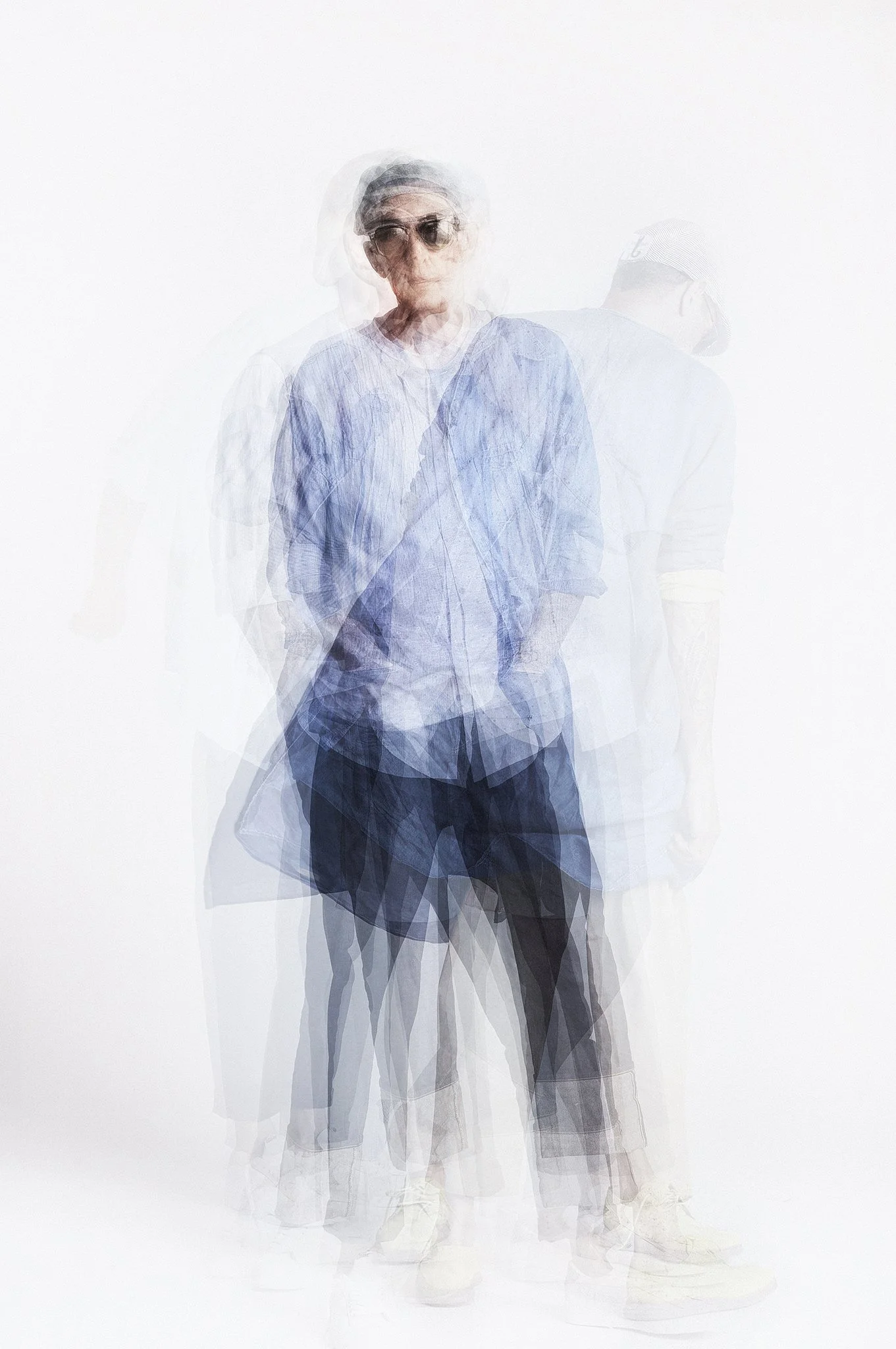 Multiple overlapping images of a Neville Trickett  in casual clothing, sunglasses, and a hat, creating a blurred, motion effect against a white background.