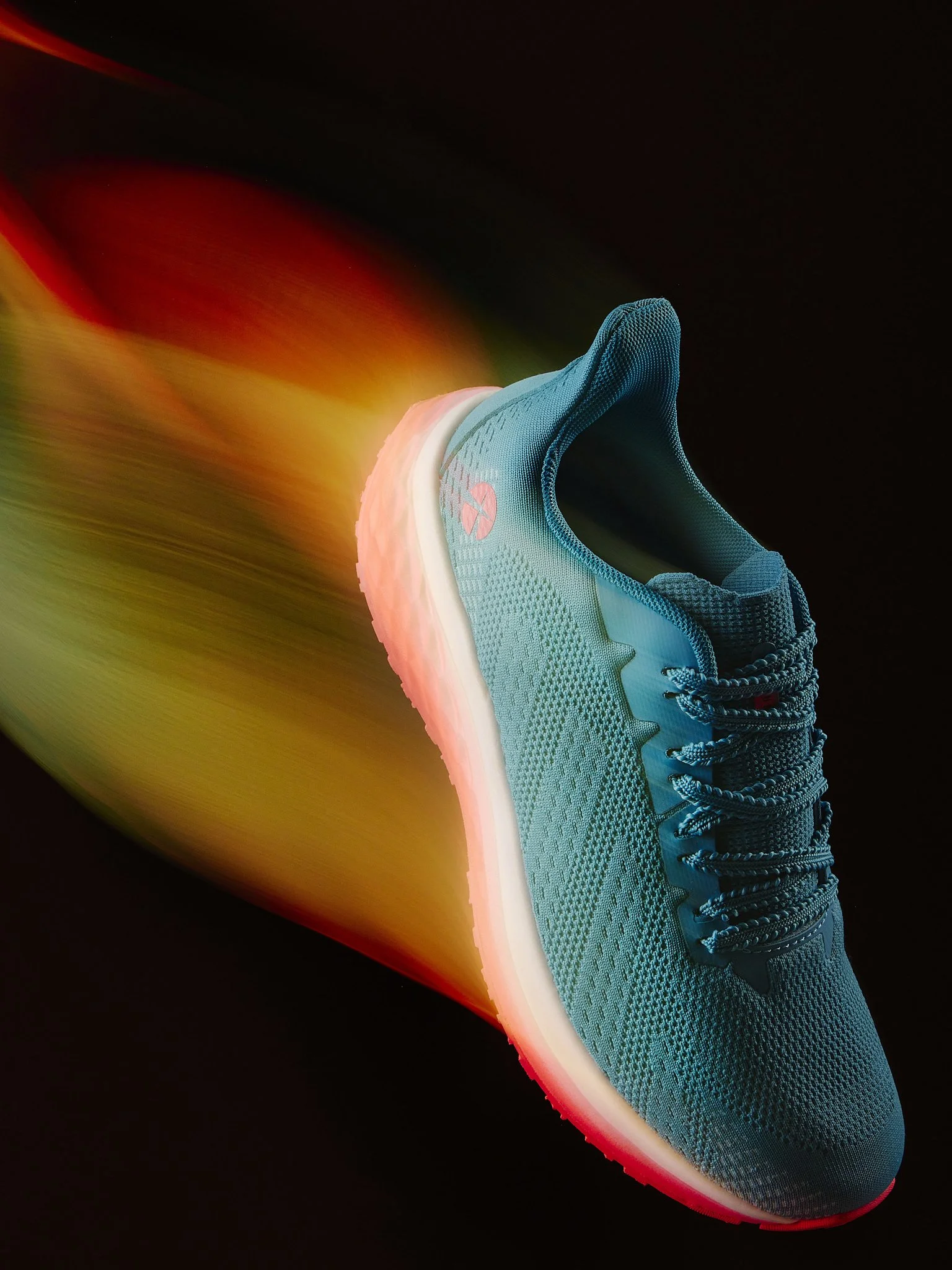 A light blue athletic shoe with a white sole and black laces against a black background, with colorful light trails in motion.