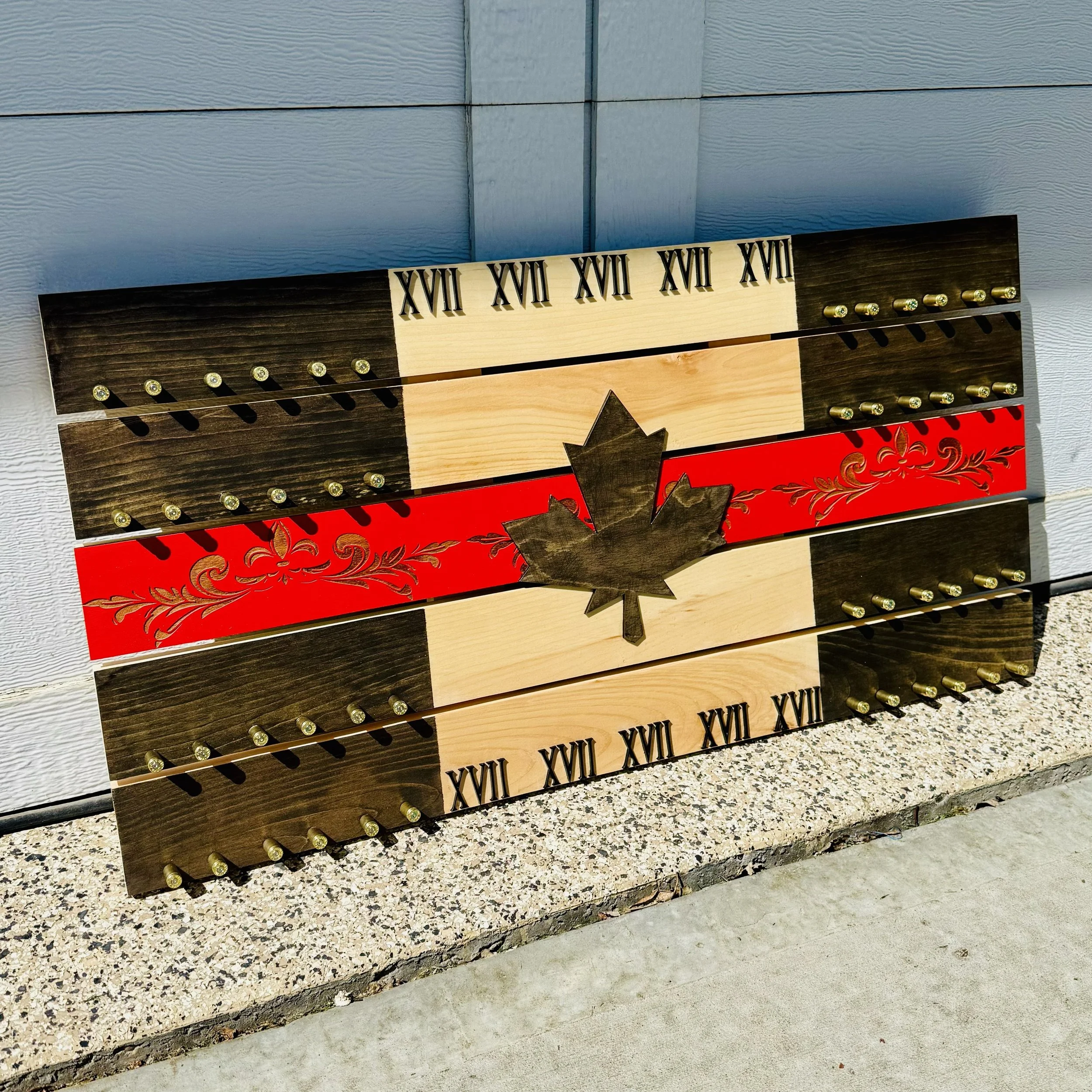 A decorative wooden sculpture featuring Roman numerals from XVII to X. The sculpture is set against a textured light blue wall and rests on a ledge with a speckled surface.