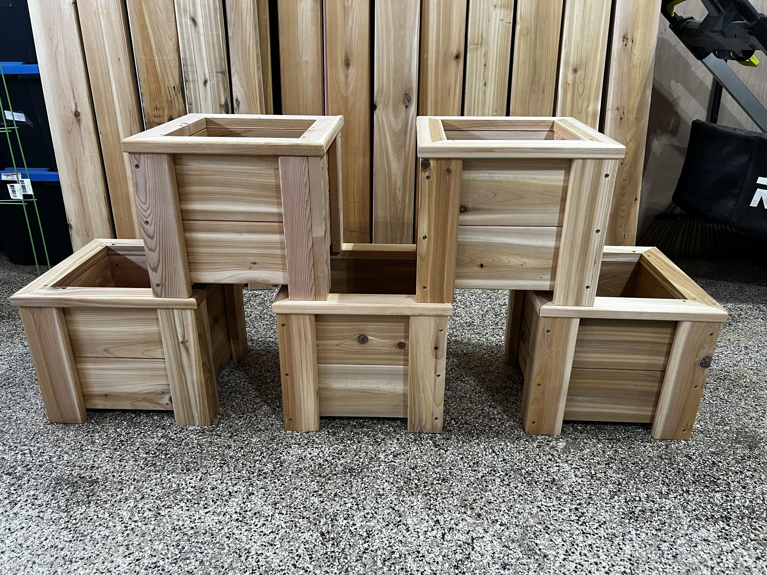 Multiple unfinished wooden flower boxes and a wooden privacy fence in a store display.