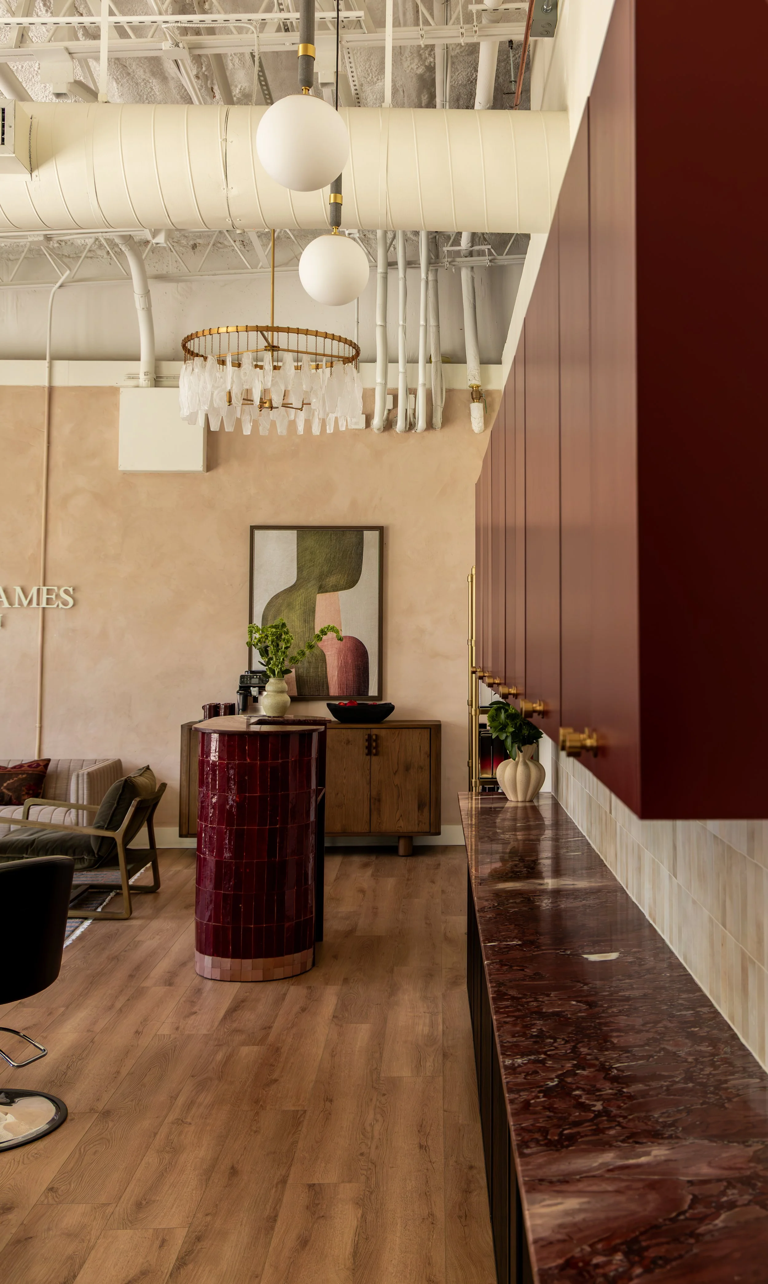 Interior of a modern living space with warm wood flooring, a red marbled countertop, and decorative wall art featuring abstract organic shapes.