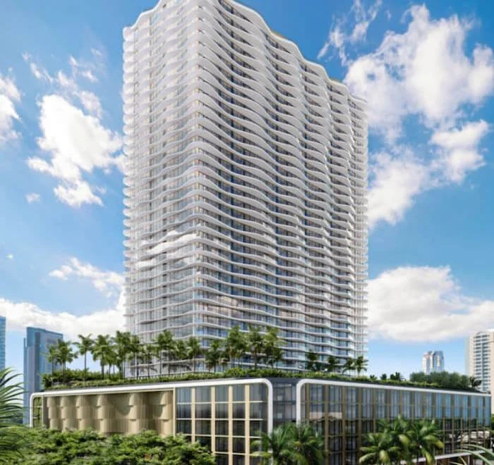 A tall modern high-rise building with wavy balconies in a cityscape with palm trees, under a blue sky with clouds.