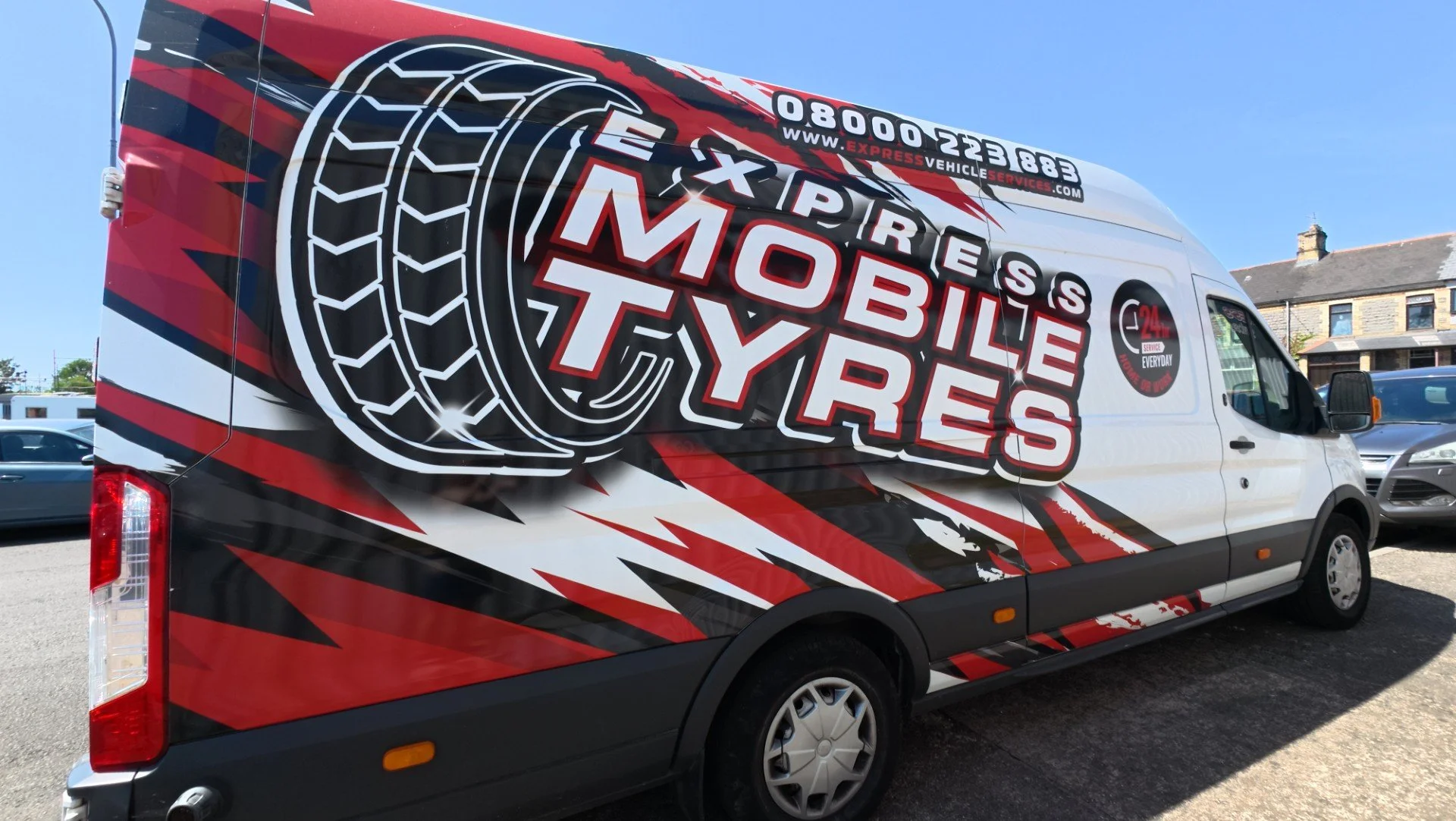 Commercial vehicle with tire repair service advertisement, featuring large tire graphics and text about mobile tire services, and contact information on top.