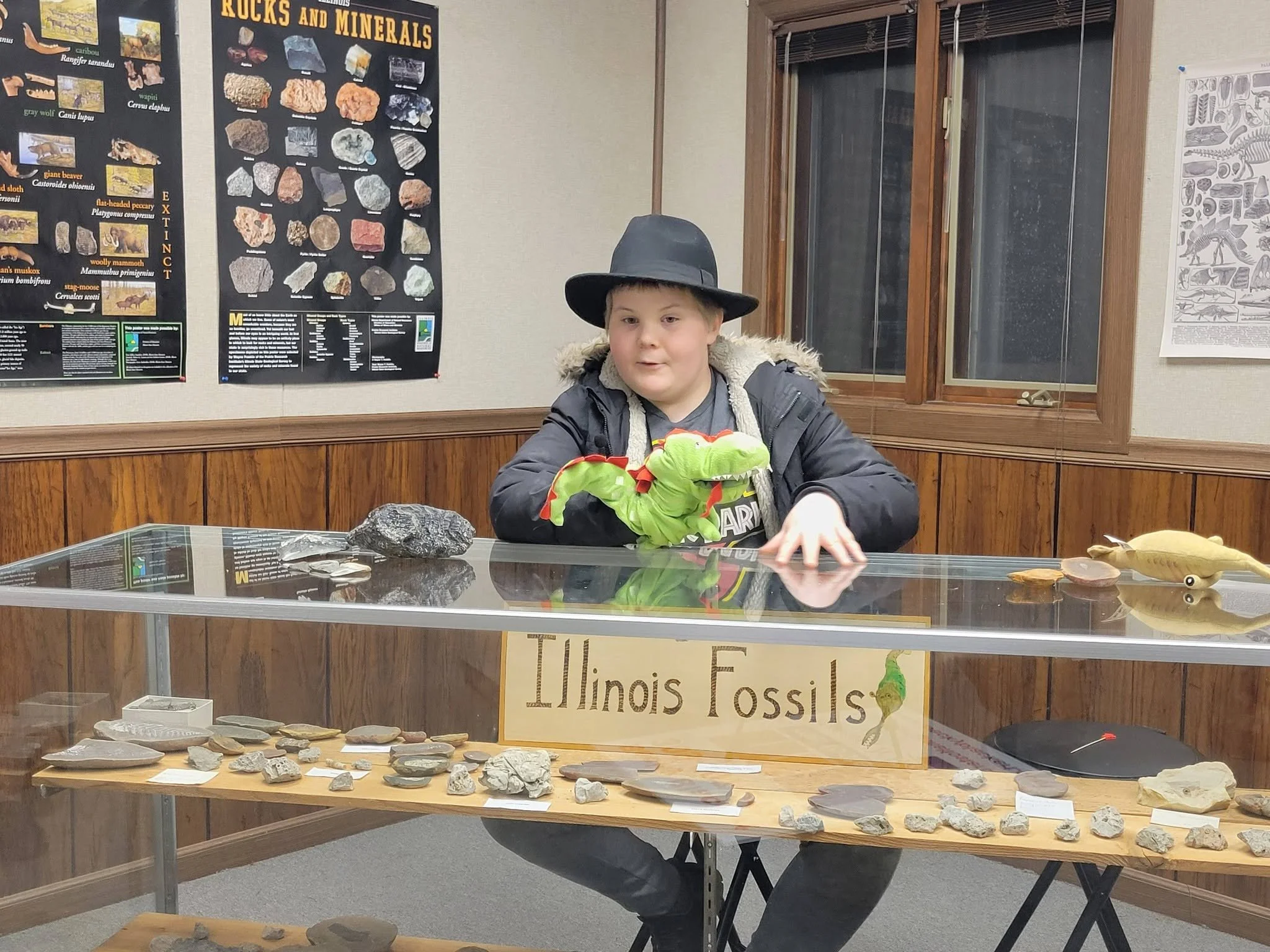 Anderson Taylor seated behind Illinois fossil specimens in the museum’s rocks and minerals gallery.