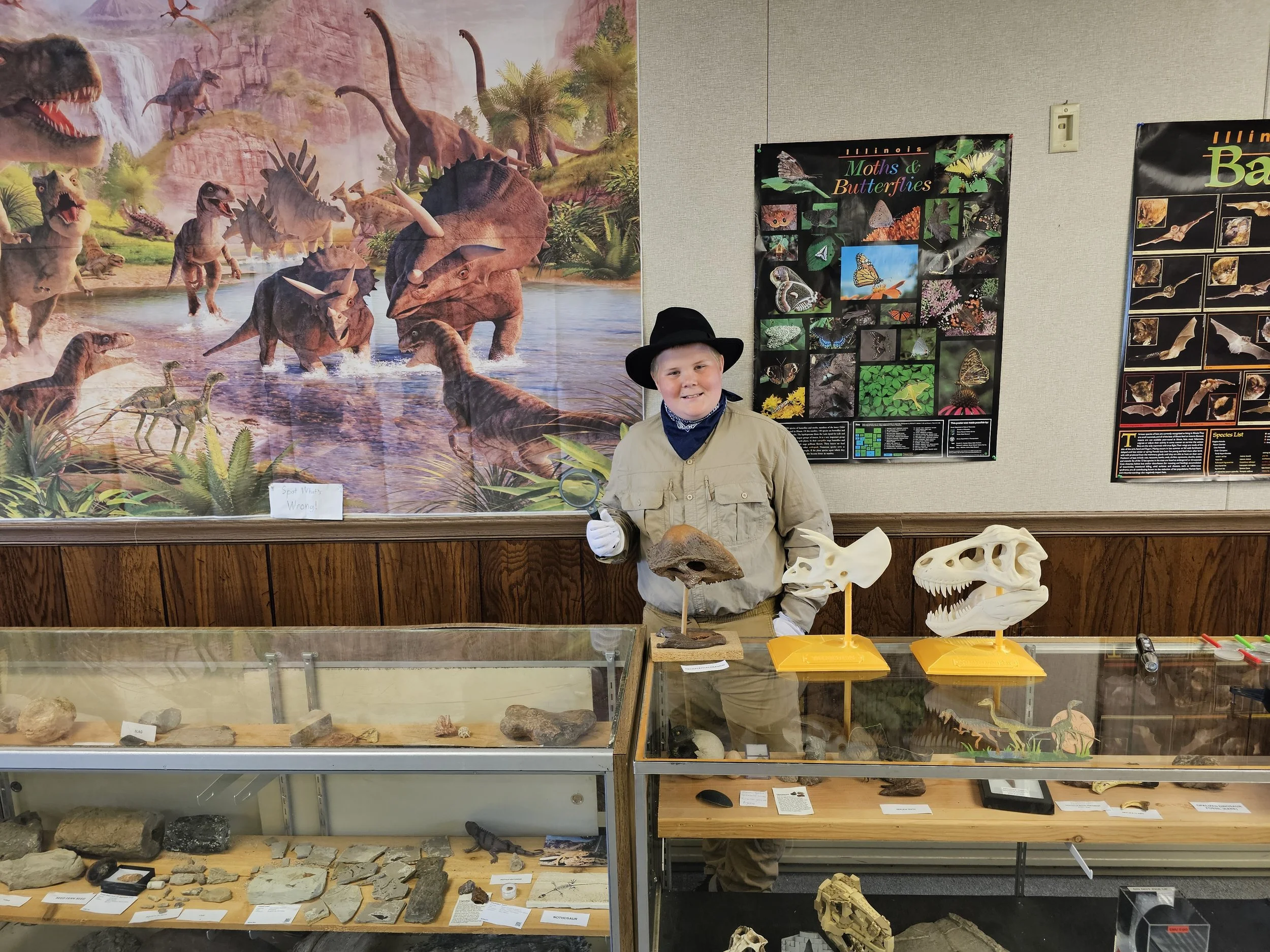 Anderson Taylor stands behind fossil and dinosaur displays inside Cambridge Natural History Museum.