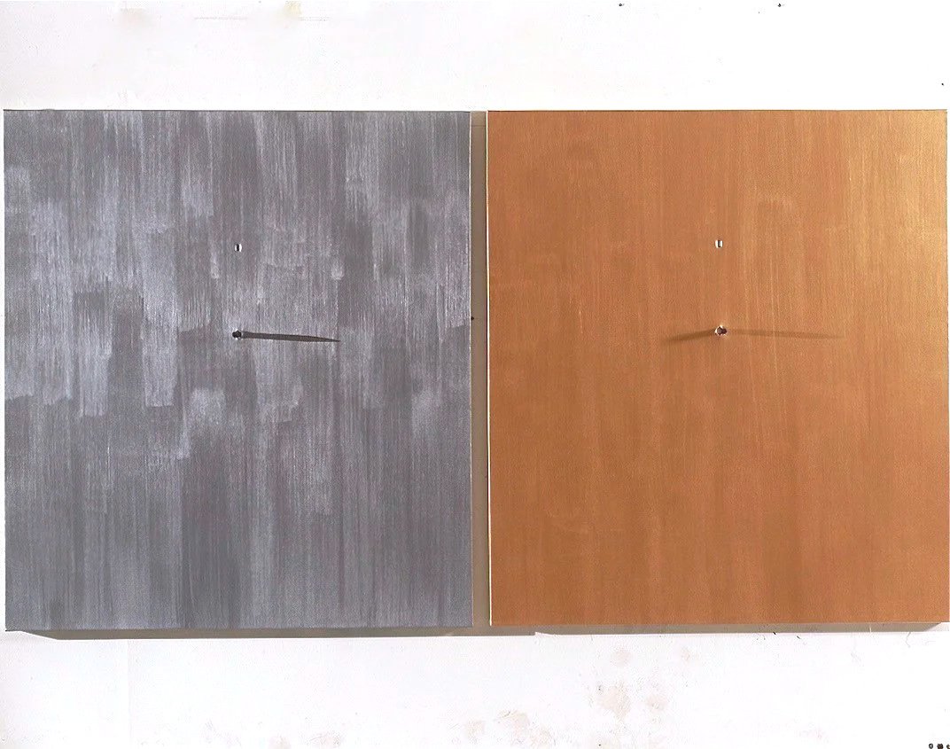 Two wooden panels, one gray and one brown, are mounted on a white wall with visible hooks and strings hanging from their centers.