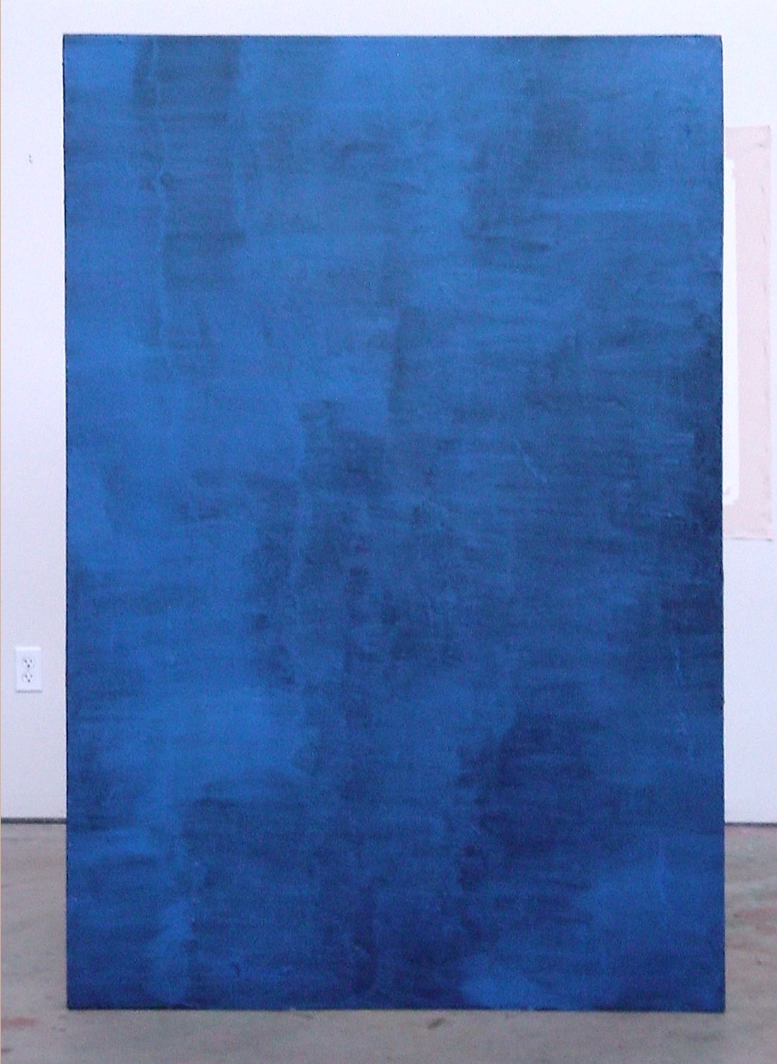 Large abstract blue painting mounted on a white wall in an art gallery.